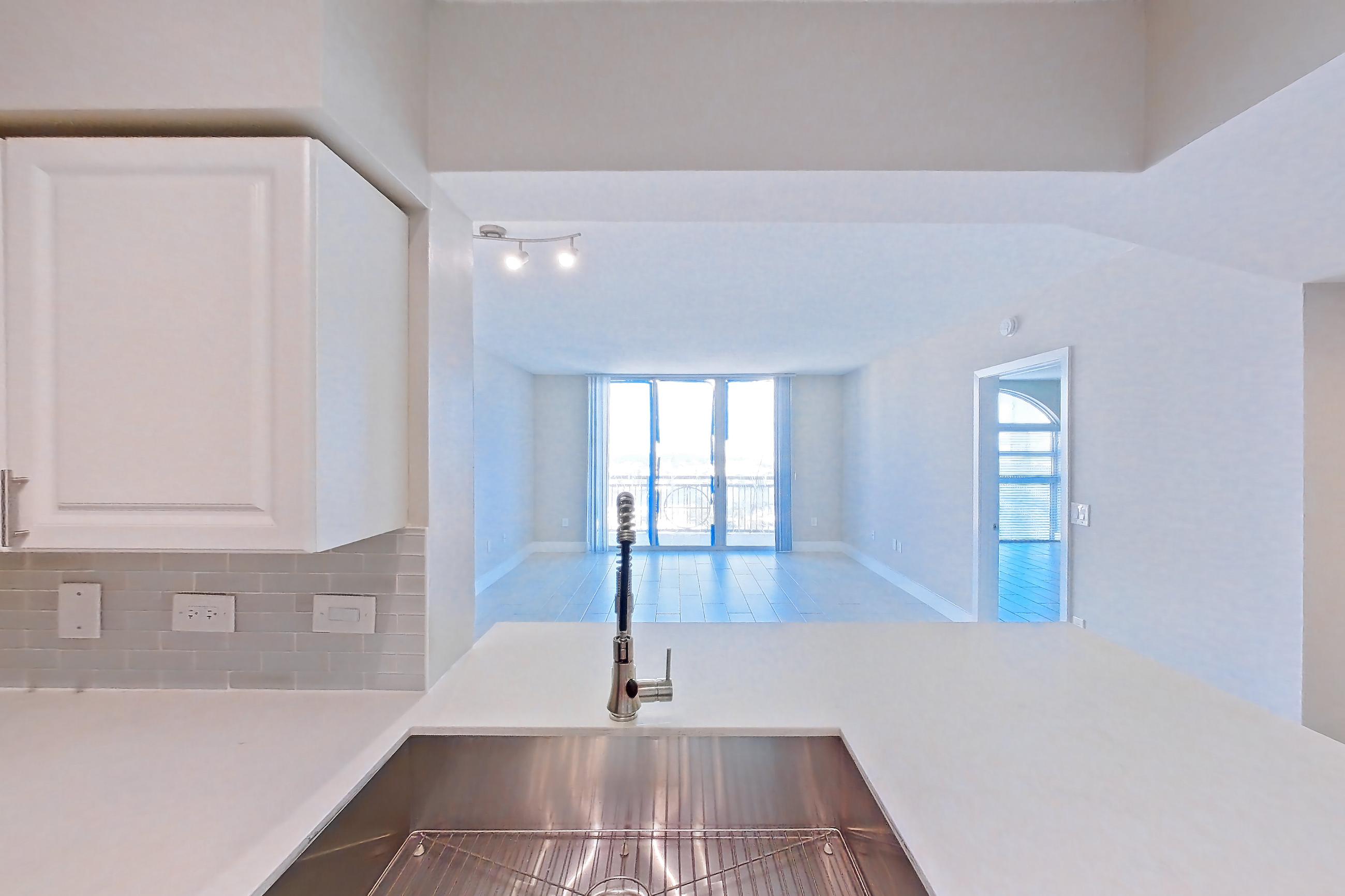 Kitchen with dishwasher, light countertops, light stone countertops, light tile flooring, light wood-finish flooring, oven/range, refrigerator, stainless steel appliances, and wood-look tile flooring, Apartment 1706 at Sunrise Harbor