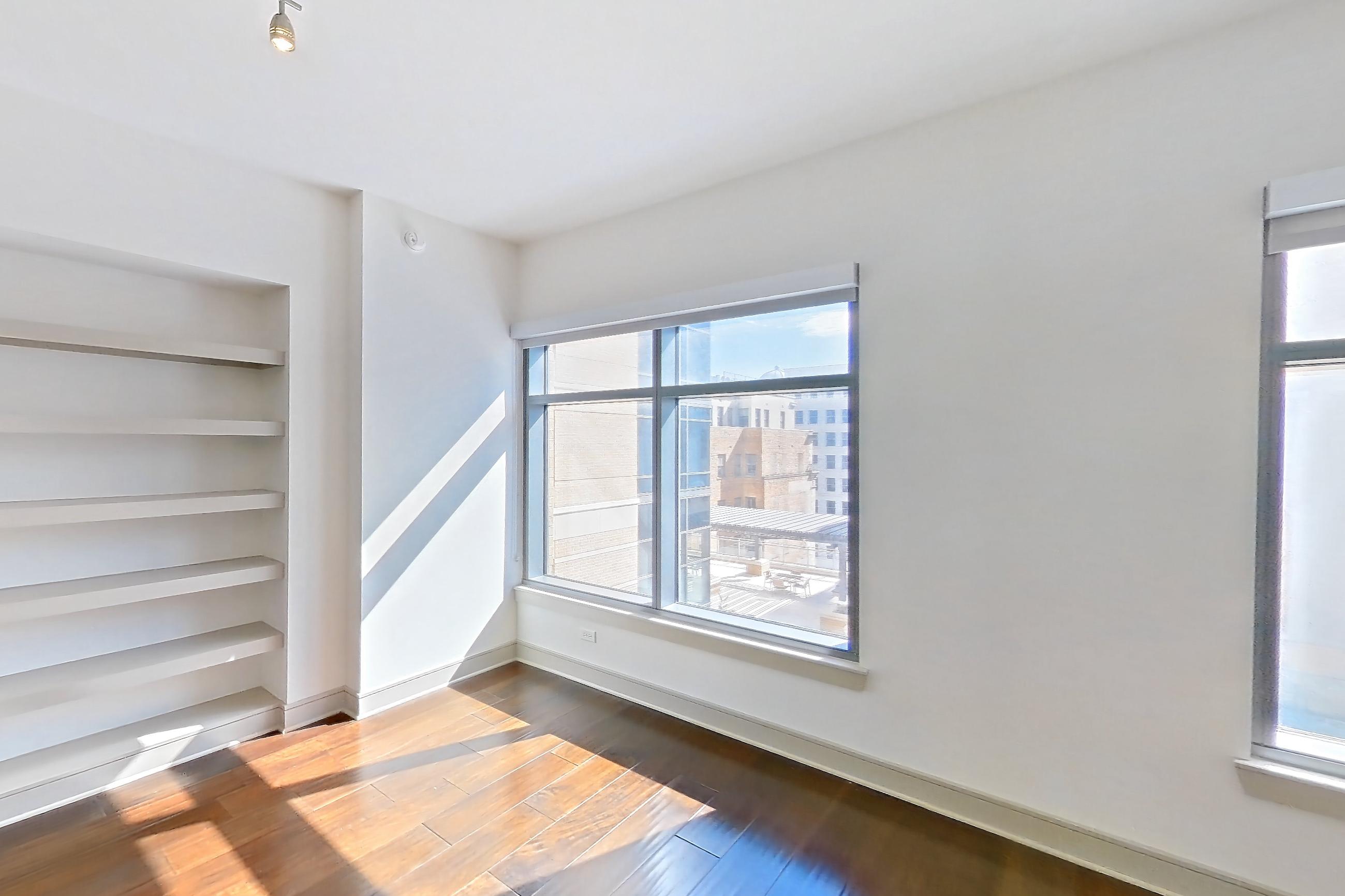 Living room with dark wood-finish flooring, dishwasher, light countertops, refrigerator, stainless steel appliances, water & ice dispenser, and wood-finish flooring, Apartment 1001 at Aris Market Square