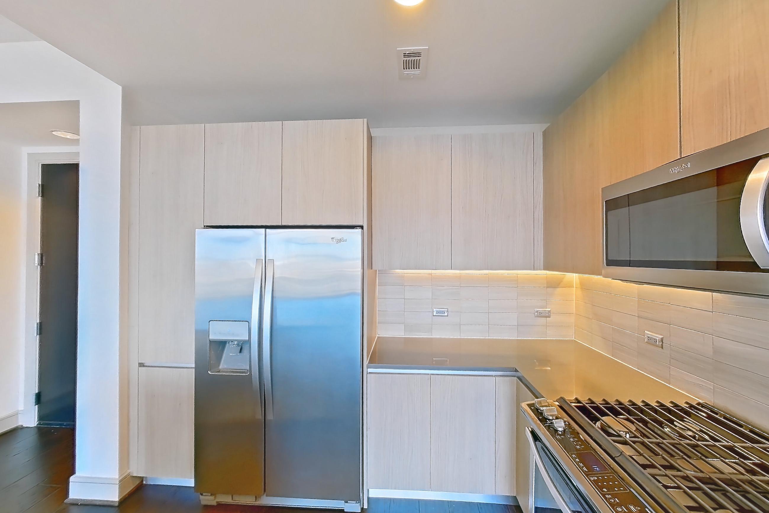 Kitchen with dark wood-finish flooring, dishwasher, gas range, light countertops, oven/range, stainless steel appliances, and wood-finish flooring, Apartment 1608 at Aris Market Square