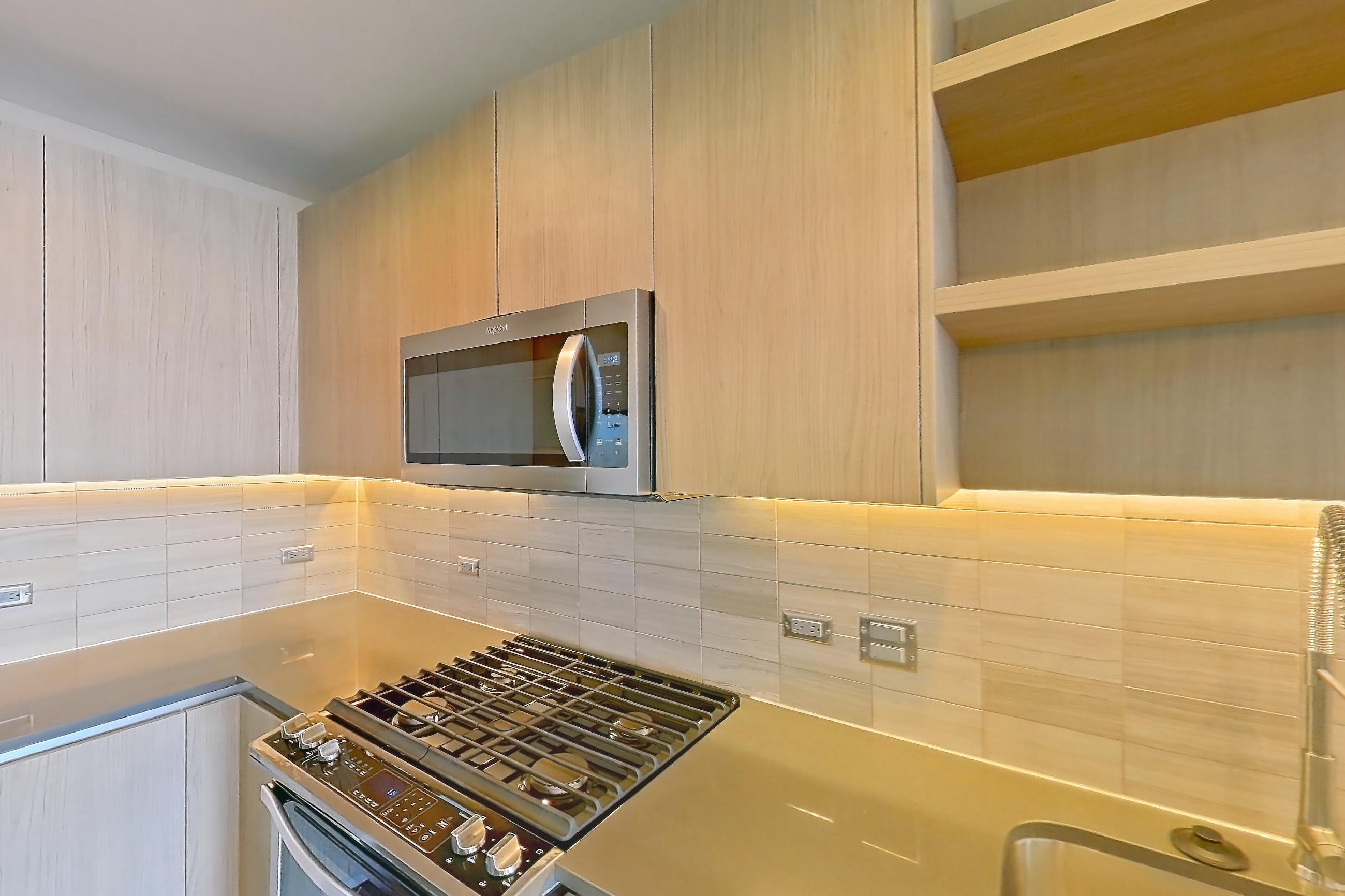 Kitchen with dark wood-finish flooring, dishwasher, gas range, light countertops, oven/range, stainless steel appliances, and wood-finish flooring, Apartment 1608 at Aris Market Square