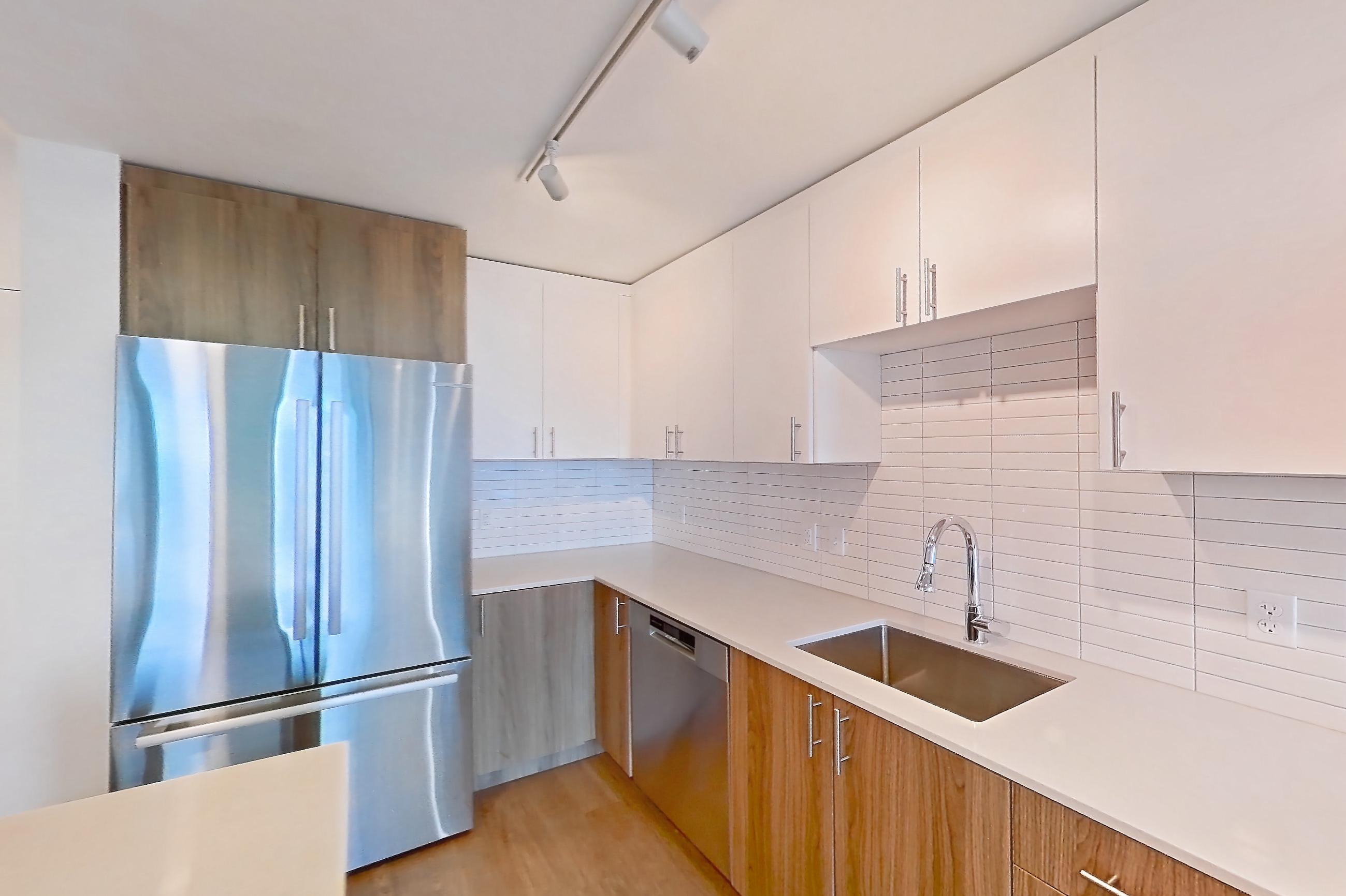 Kitchen with dishwasher, electric range, light countertops, light stone countertops, light wood-finish flooring, microwave, oven/range, refrigerator, and stainless steel appliances, Apartment 1111 at Cortland Rosslyn