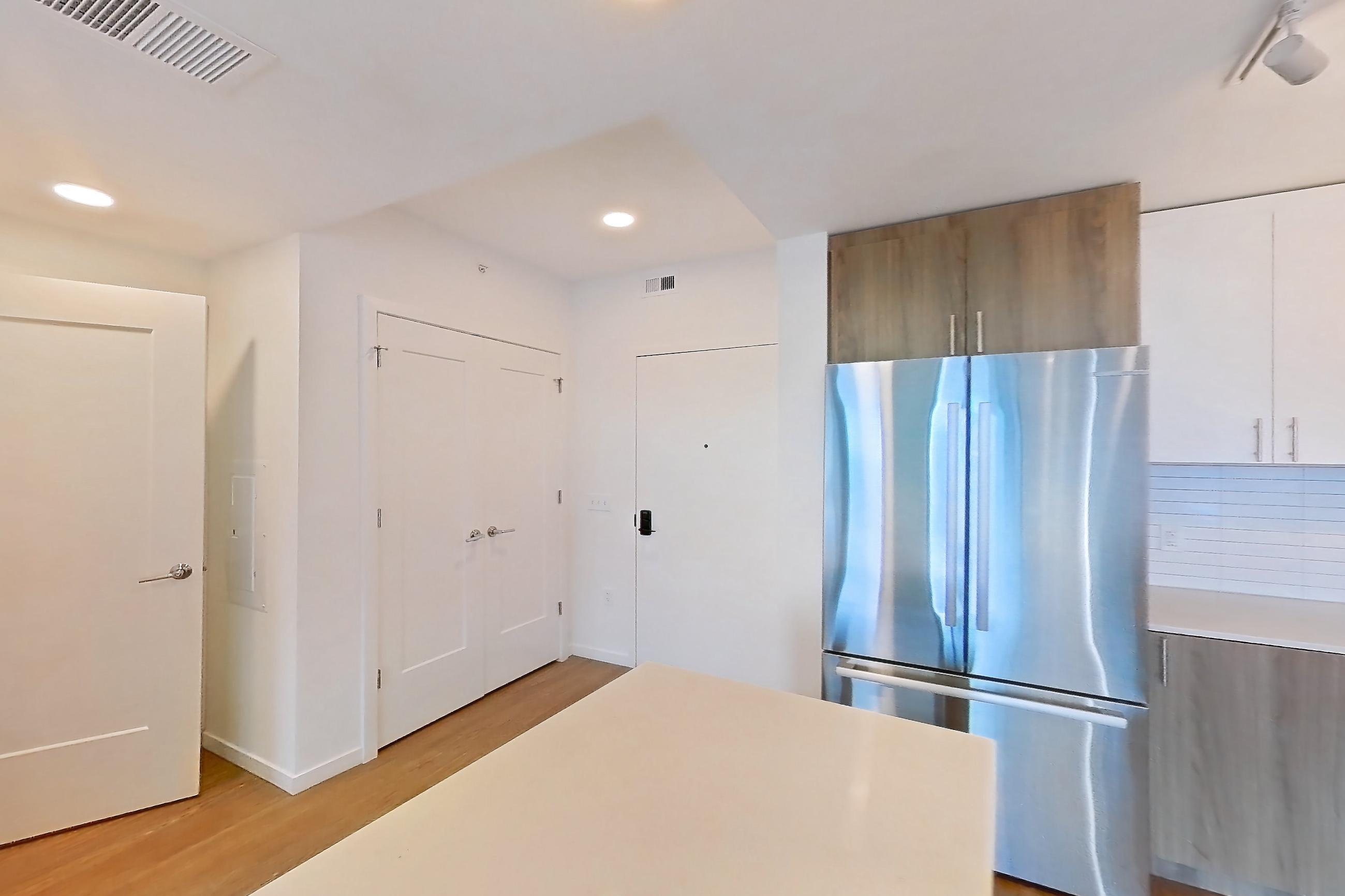Kitchen with dishwasher, electric range, light countertops, light stone countertops, light wood-finish flooring, microwave, oven/range, refrigerator, and stainless steel appliances, Apartment 1111 at Cortland Rosslyn