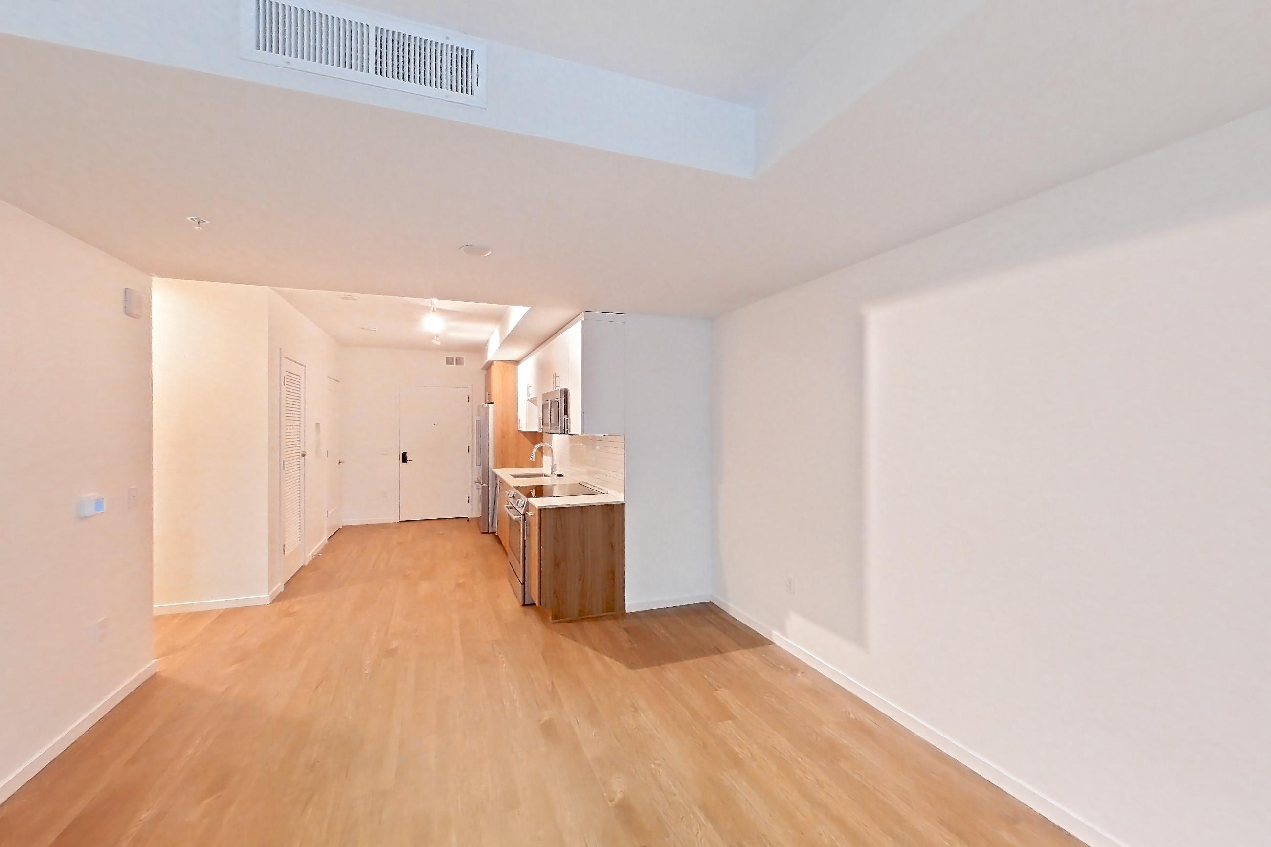 Living room with electric range, light wood-finish flooring, oven/range, and stainless steel appliances, Apartment 1406 at Cortland Rosslyn
