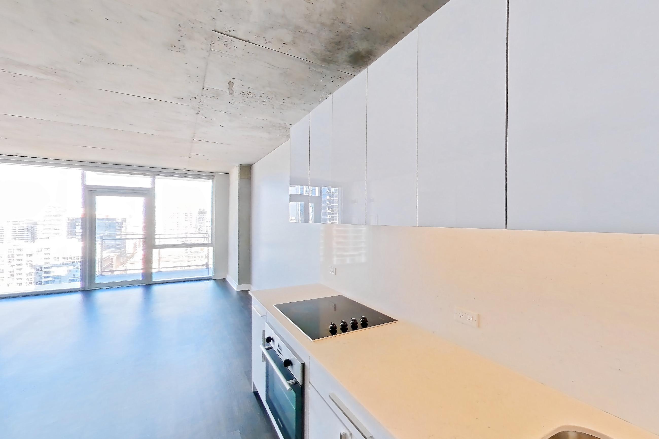 Kitchen with black appliances, cooktop, dark wood-finish flooring, electric cooktop, and light stone countertops, Apartment 2103 at 220 WIL