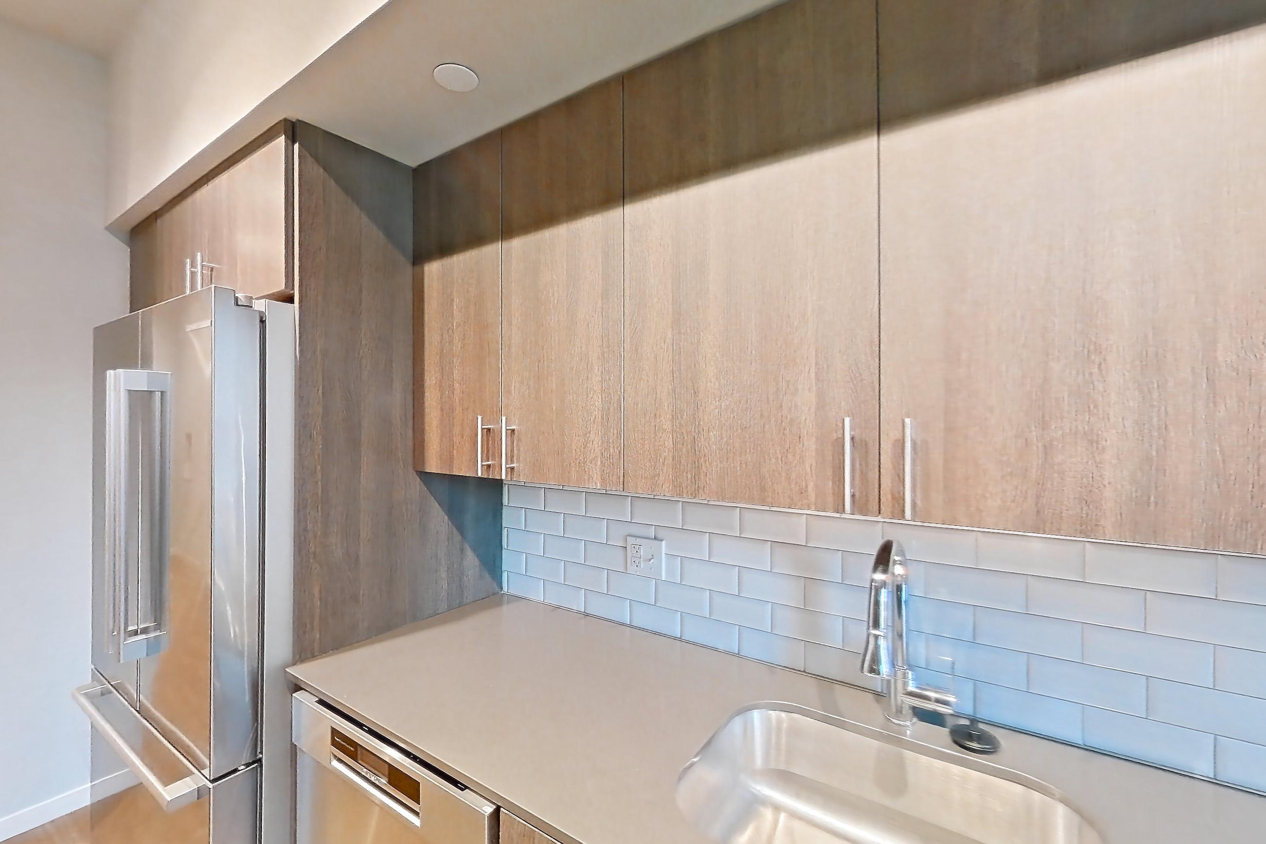 Kitchen with dishwasher, electric range, light stone countertops, light wood-finish flooring, oven/range, refrigerator, and stainless steel appliances, Apartment 1-0310 at Cortland Rosslyn