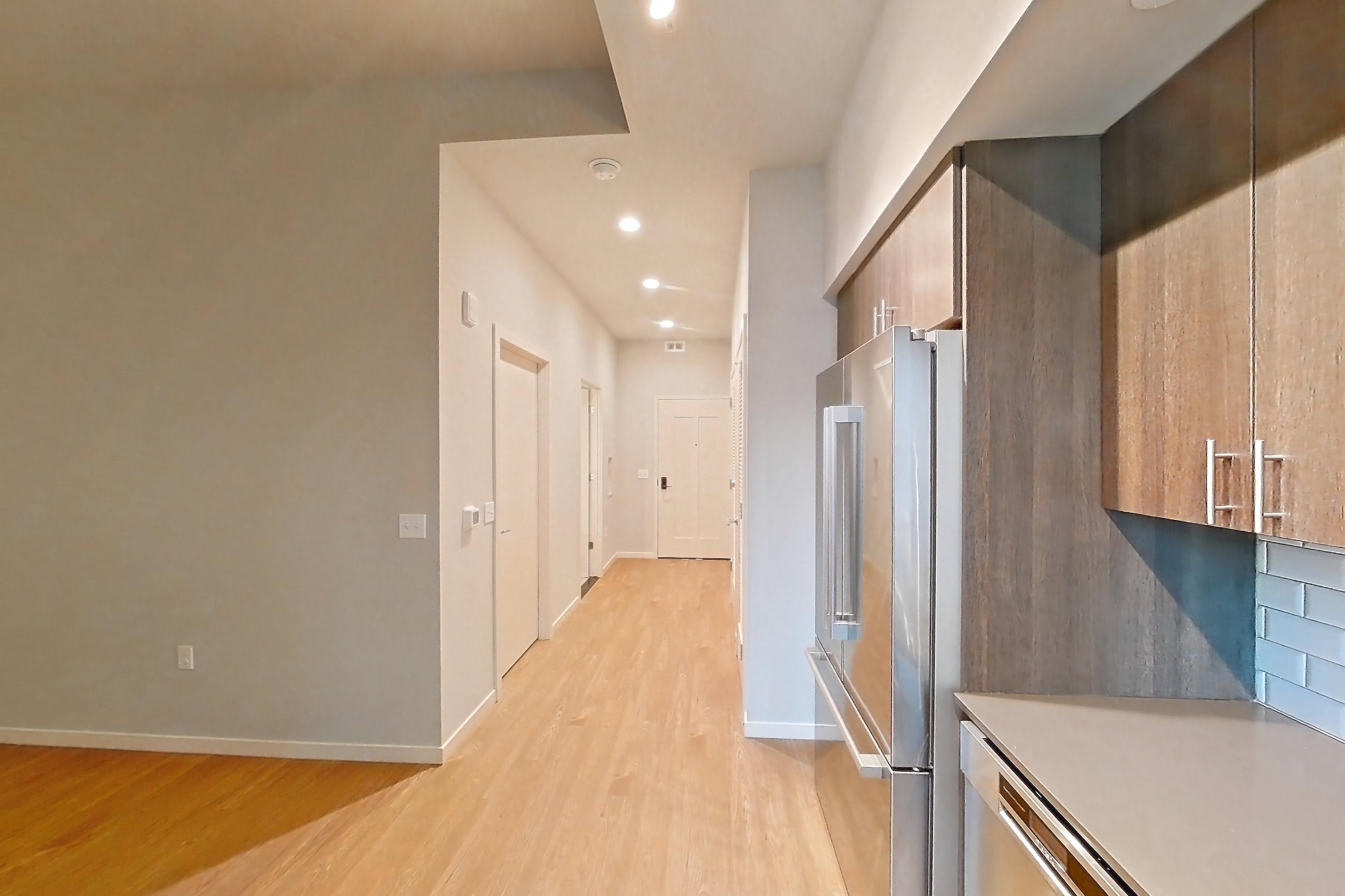 Kitchen with dishwasher, electric range, light stone countertops, light wood-finish flooring, oven/range, refrigerator, and stainless steel appliances, Apartment 1-0310 at Cortland Rosslyn