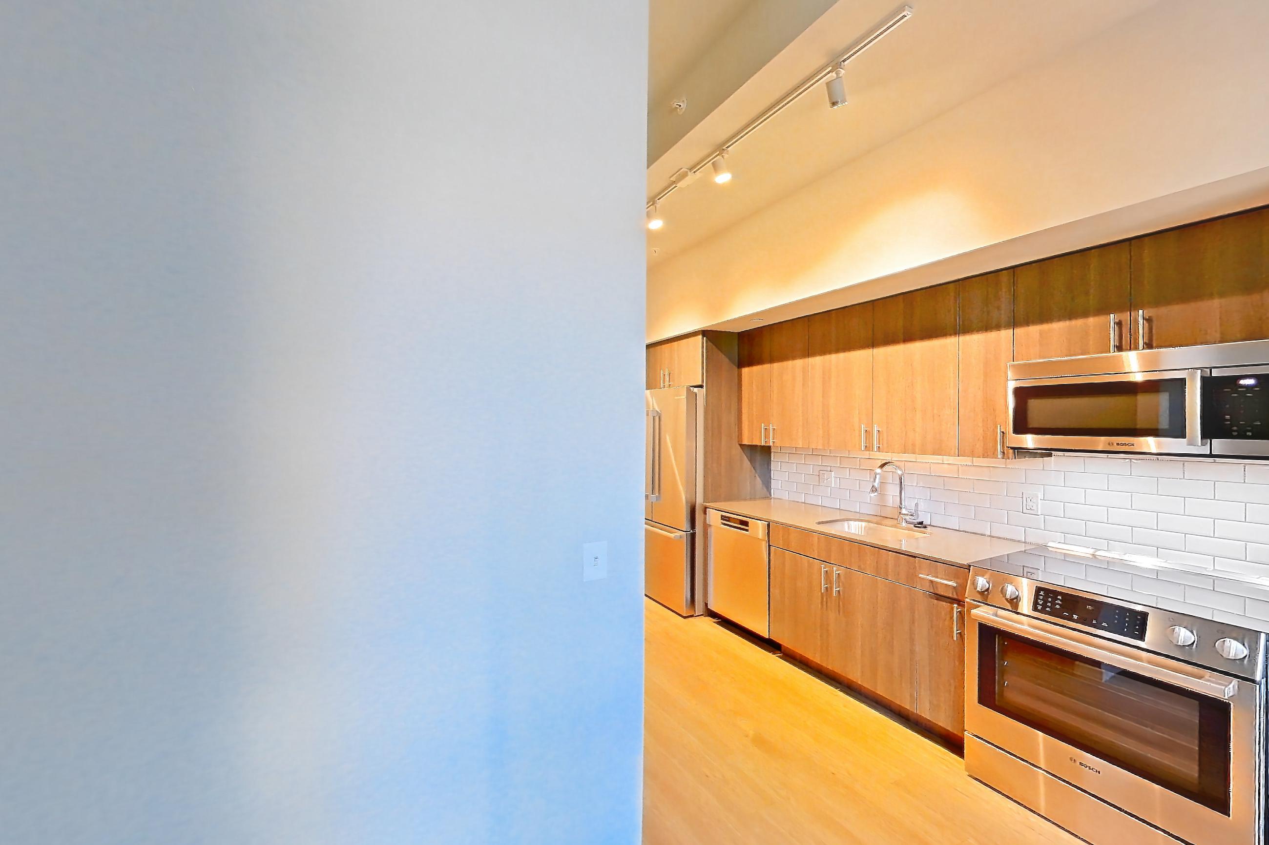 Living room with dark wood-finish flooring, light wood-finish flooring, and refrigerator, Apartment 1-0310 at Cortland Rosslyn