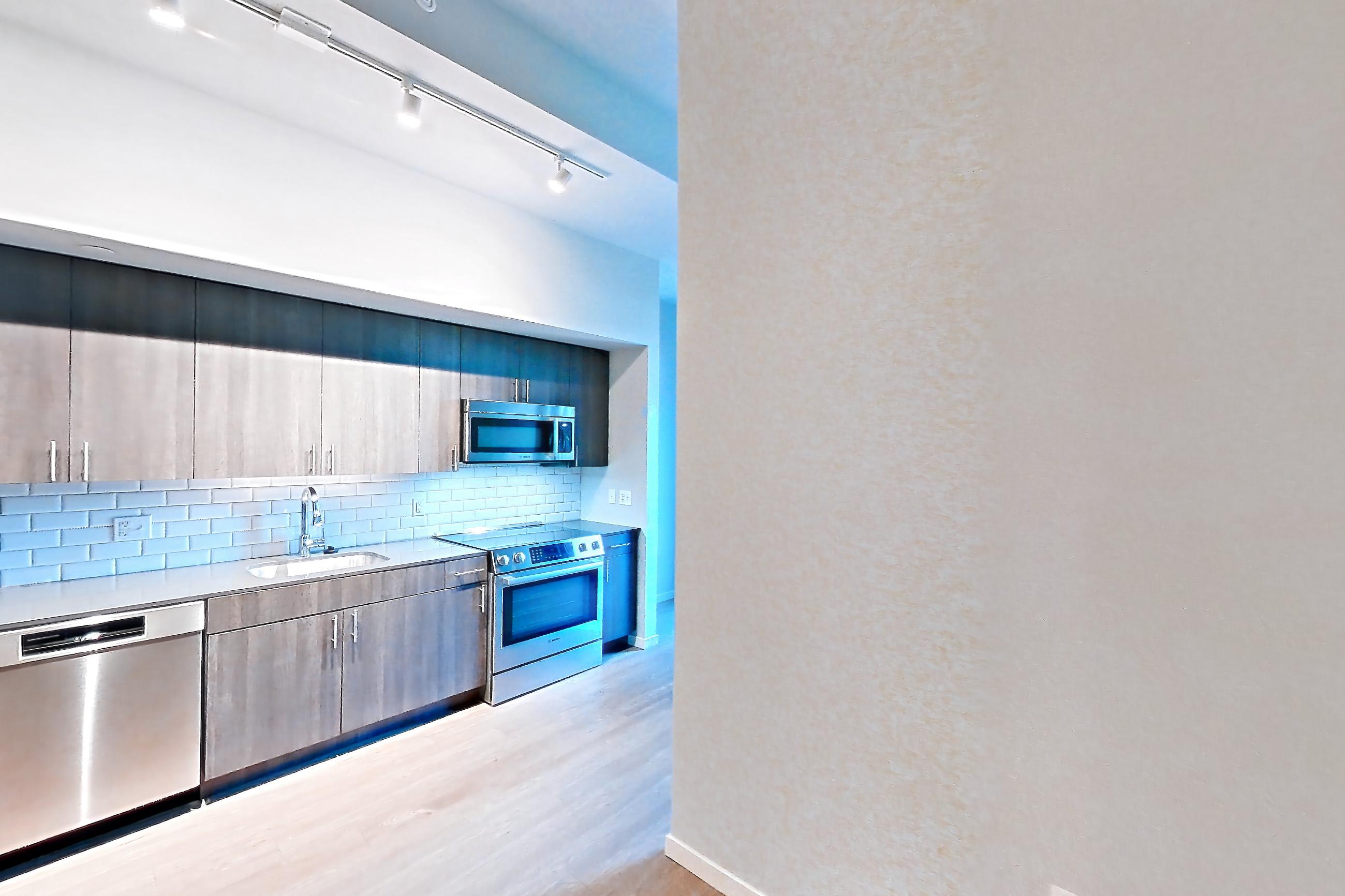 Living space with dishwasher, electric range, light countertops, light wood-finish flooring, oven/range, refrigerator, and stainless steel appliances, Apartment 1-0310 at Cortland Rosslyn