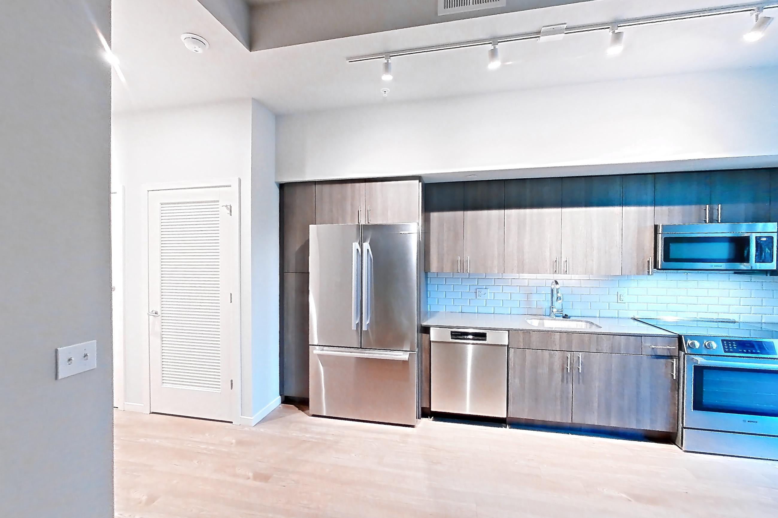 Living space with dishwasher, electric range, light countertops, light wood-finish flooring, oven/range, refrigerator, and stainless steel appliances, Apartment 1-0310 at Cortland Rosslyn