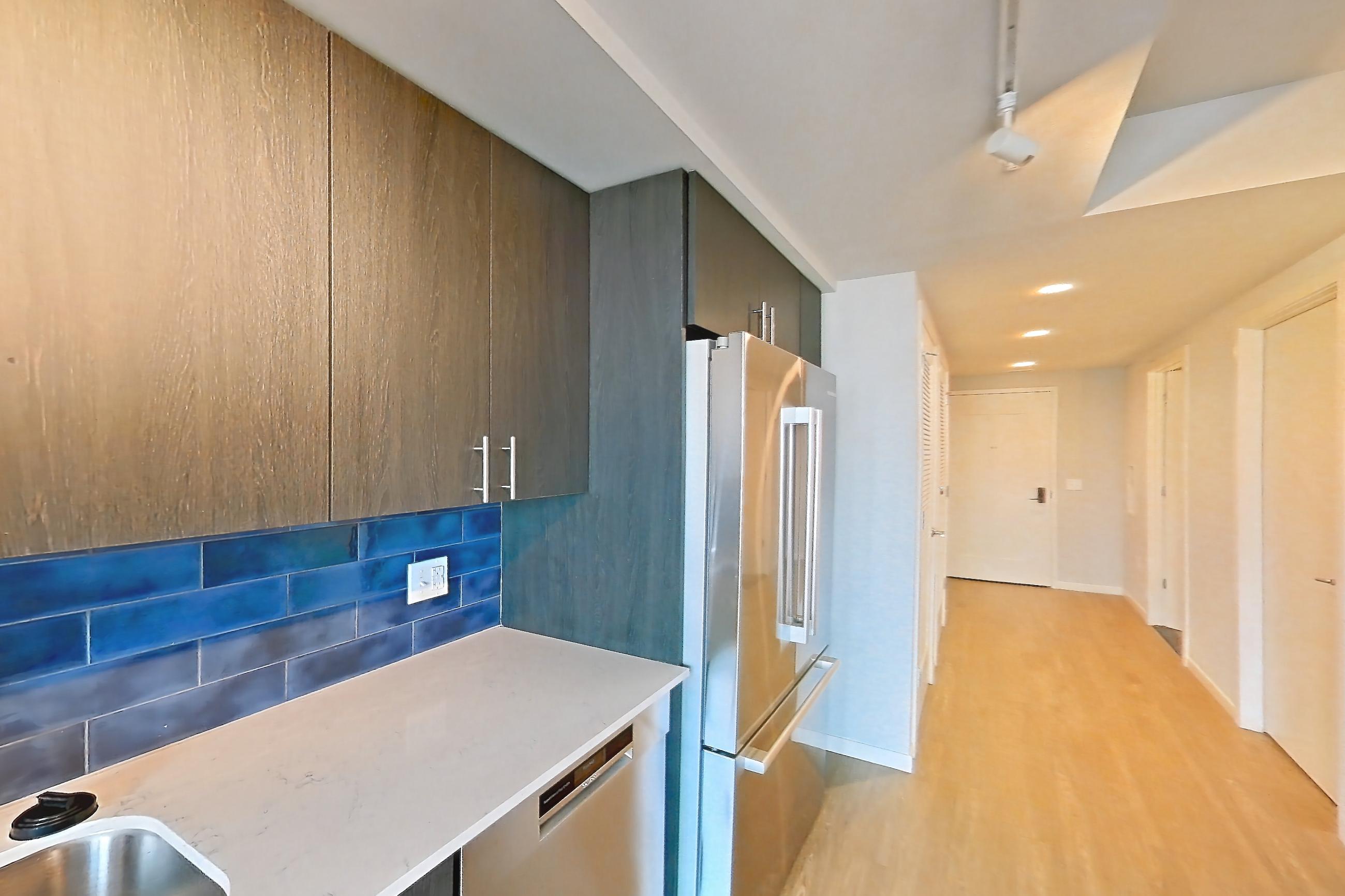 Kitchen with electric range, light stone countertops, light wood-finish flooring, oven/range, refrigerator, and stainless steel appliances, Apartment 1-2009 at Cortland Rosslyn