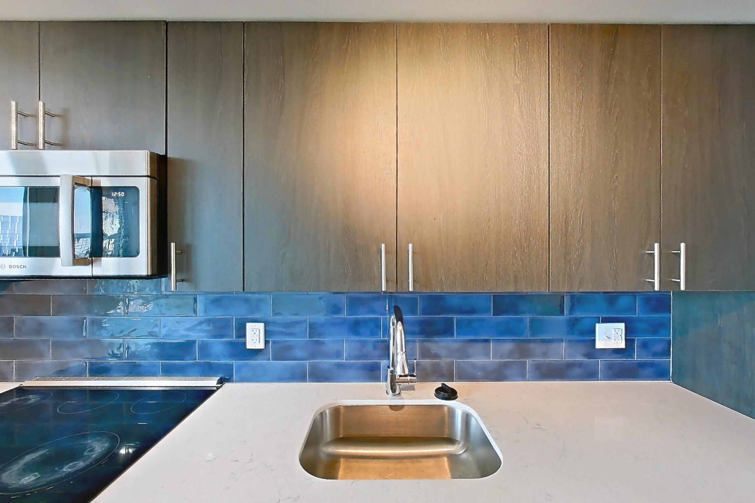 Kitchen with electric range, light stone countertops, light wood-finish flooring, oven/range, refrigerator, and stainless steel appliances, Apartment 1-2009 at Cortland Rosslyn