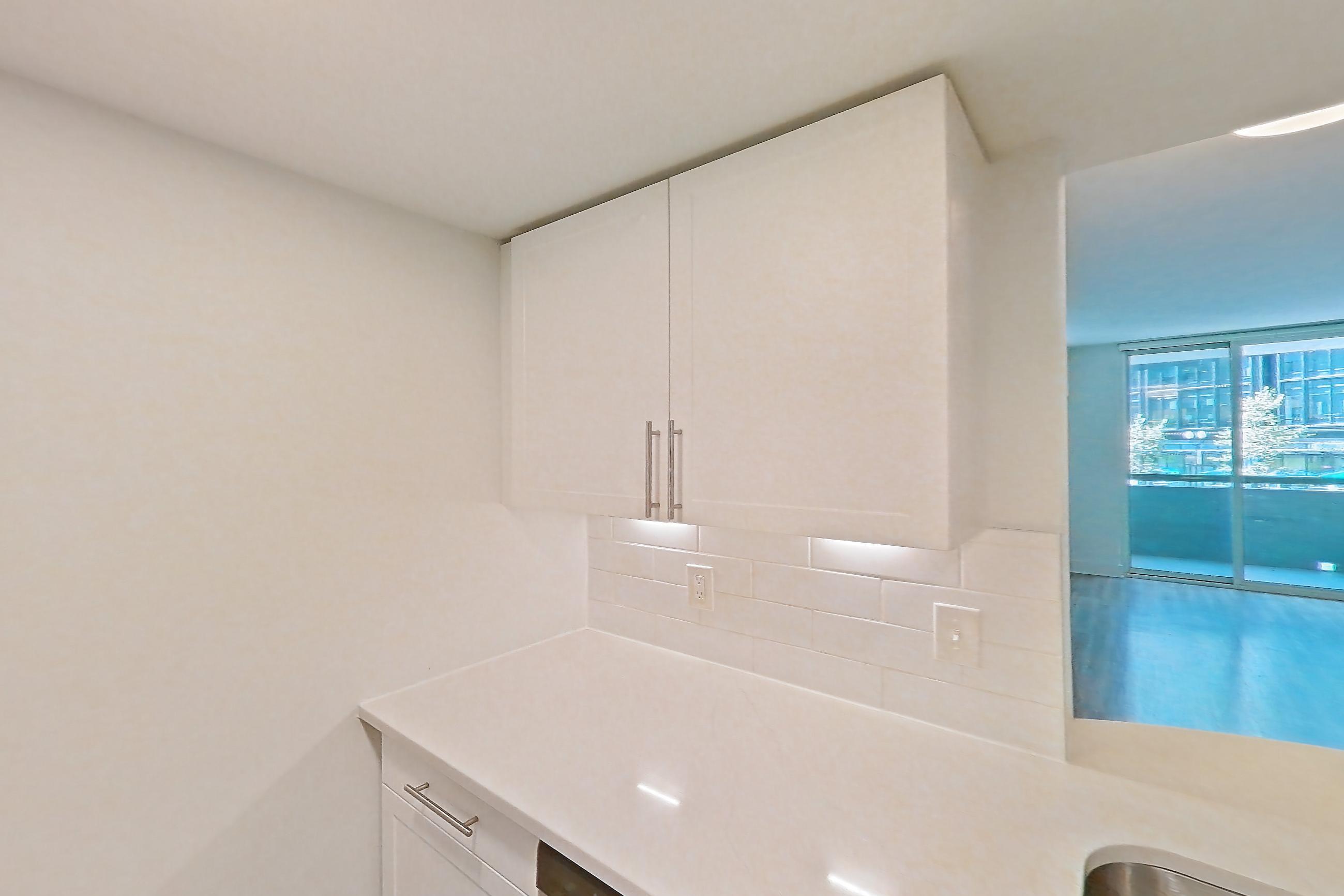 Kitchen with dishwasher, gas range, light countertops, light stone countertops, light wood-finish flooring, microwave, oven/range, refrigerator, and stainless steel appliances, Apartment 01-0208 at Cortland Pentagon City