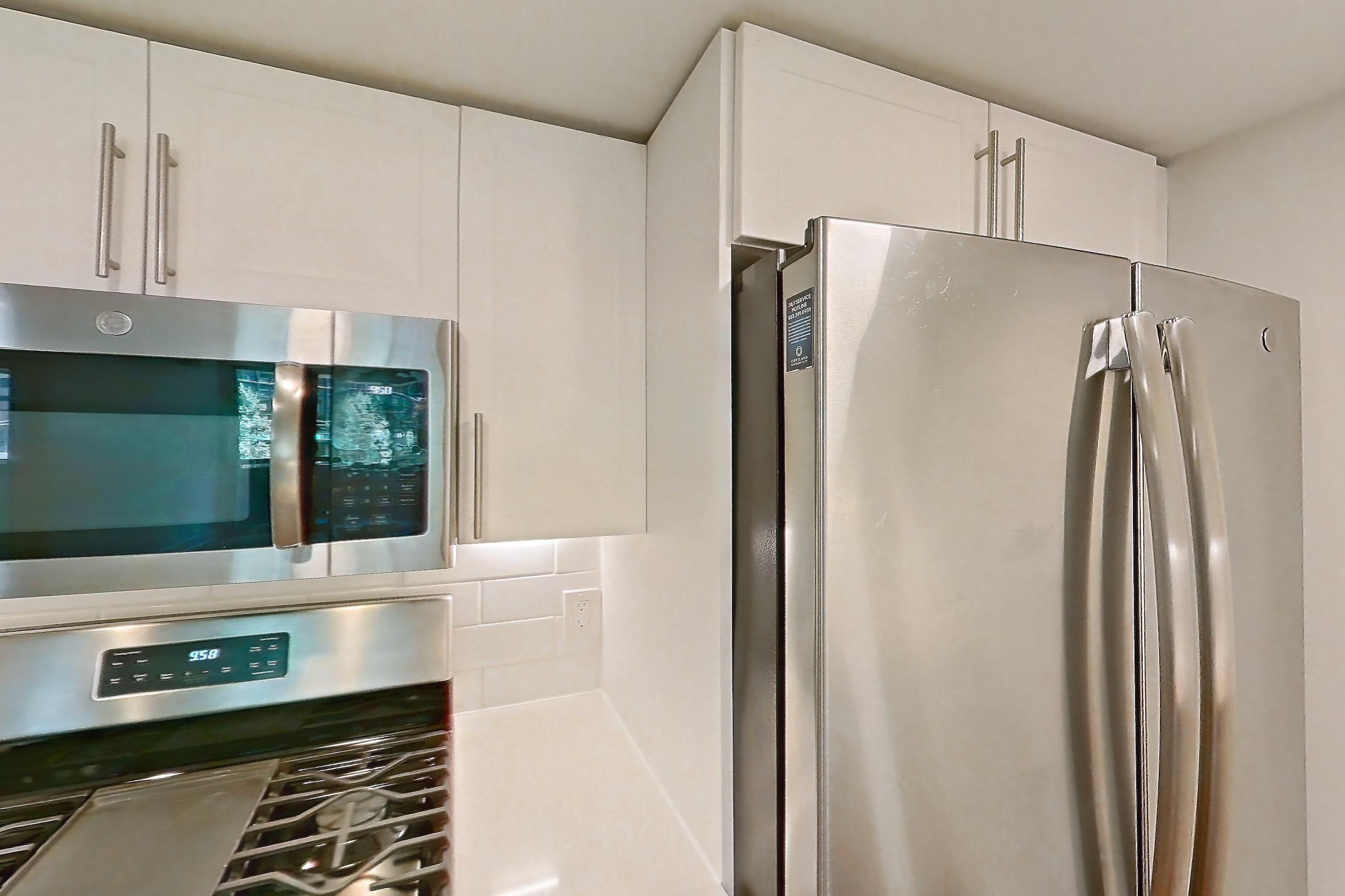 Kitchen with dishwasher, gas range, light countertops, light stone countertops, light wood-finish flooring, microwave, oven/range, refrigerator, and stainless steel appliances, Apartment 01-0208 at Cortland Pentagon City
