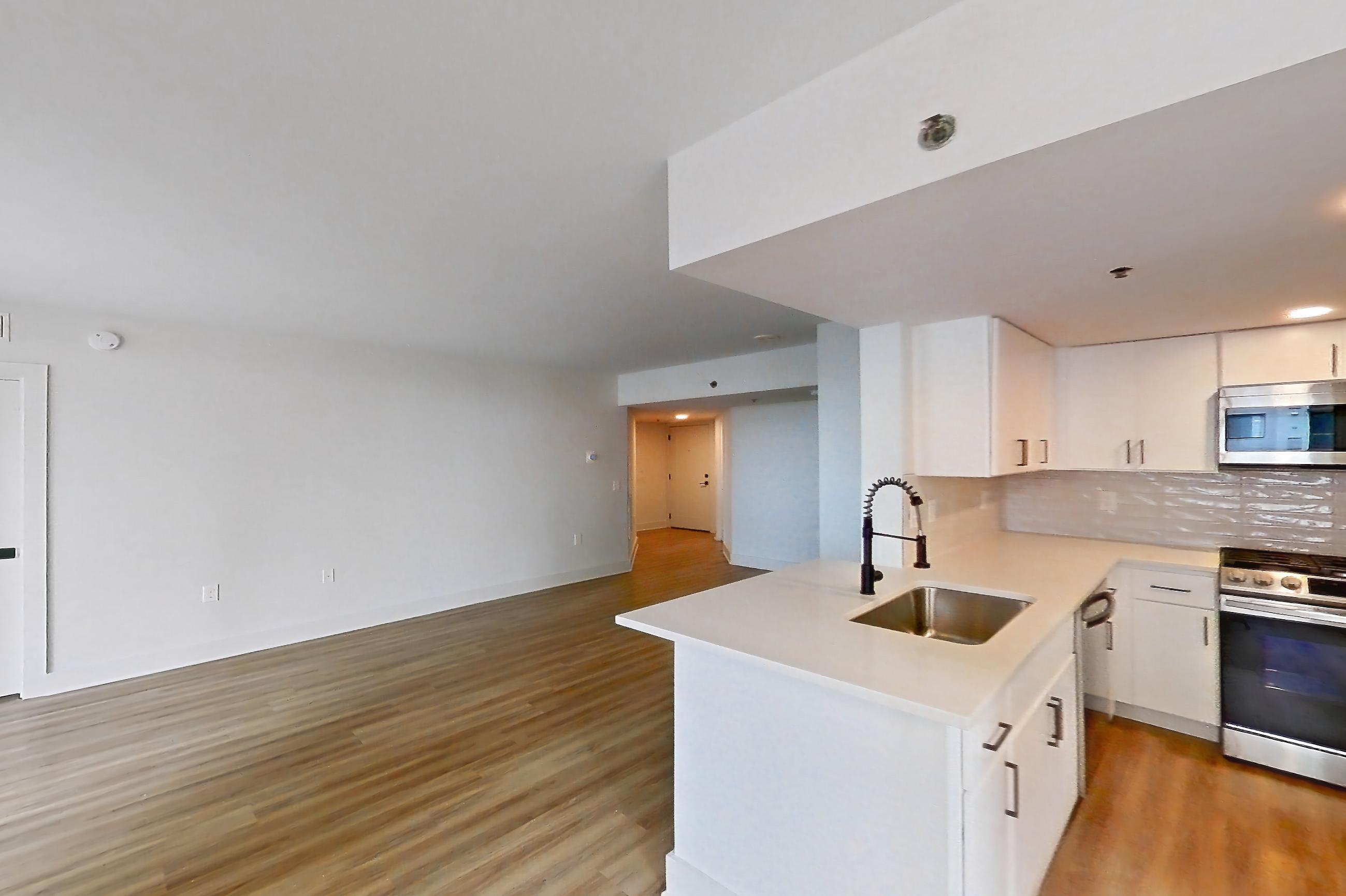Living space with dishwasher, gas range, light countertops, light stone countertops, light wood-finish flooring, oven/range, and stainless steel appliances, Apartment 02-0918 at Cortland Pentagon City