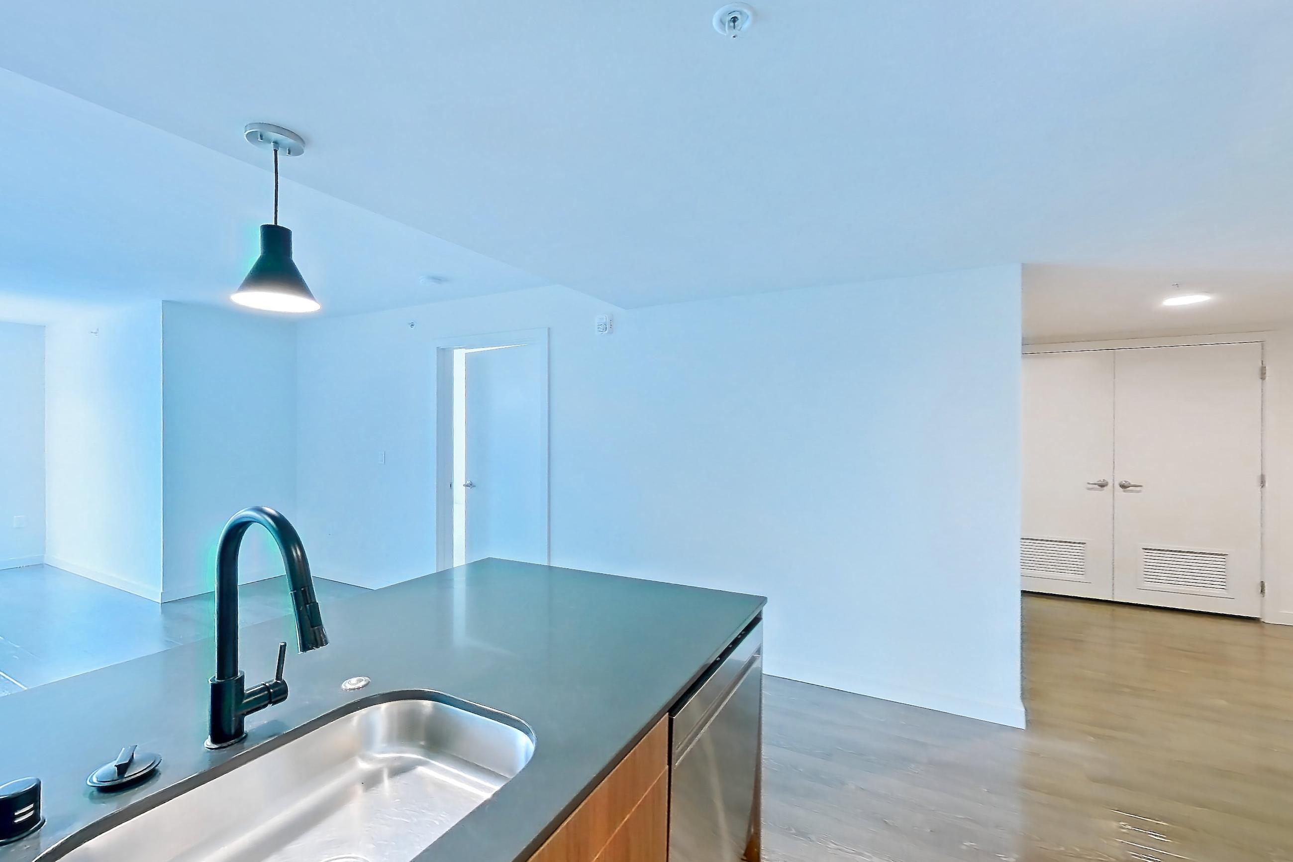 Kitchen with dark countertops, dark wood-finish flooring, dishwasher, electric range, light countertops, light wood-finish flooring, microwave, oven/range, range hood, refrigerator, and stainless steel appliances, Apartment 201 at Talisman