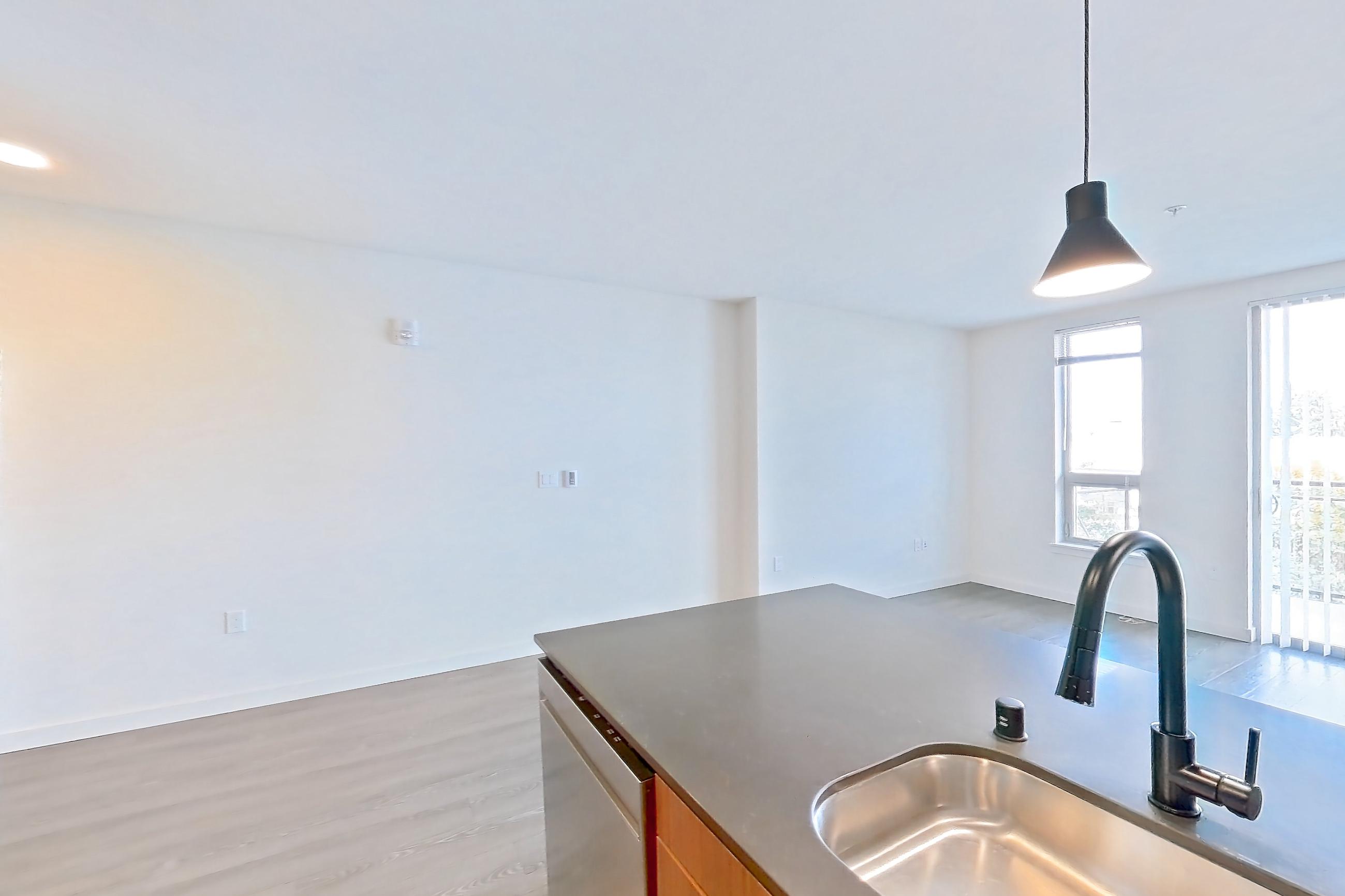Kitchen with dark countertops, dishwasher, electric range, light countertops, light wood-finish flooring, microwave, oven/range, range hood, refrigerator, stainless steel appliances, and white appliances, Apartment 440 at Talisman