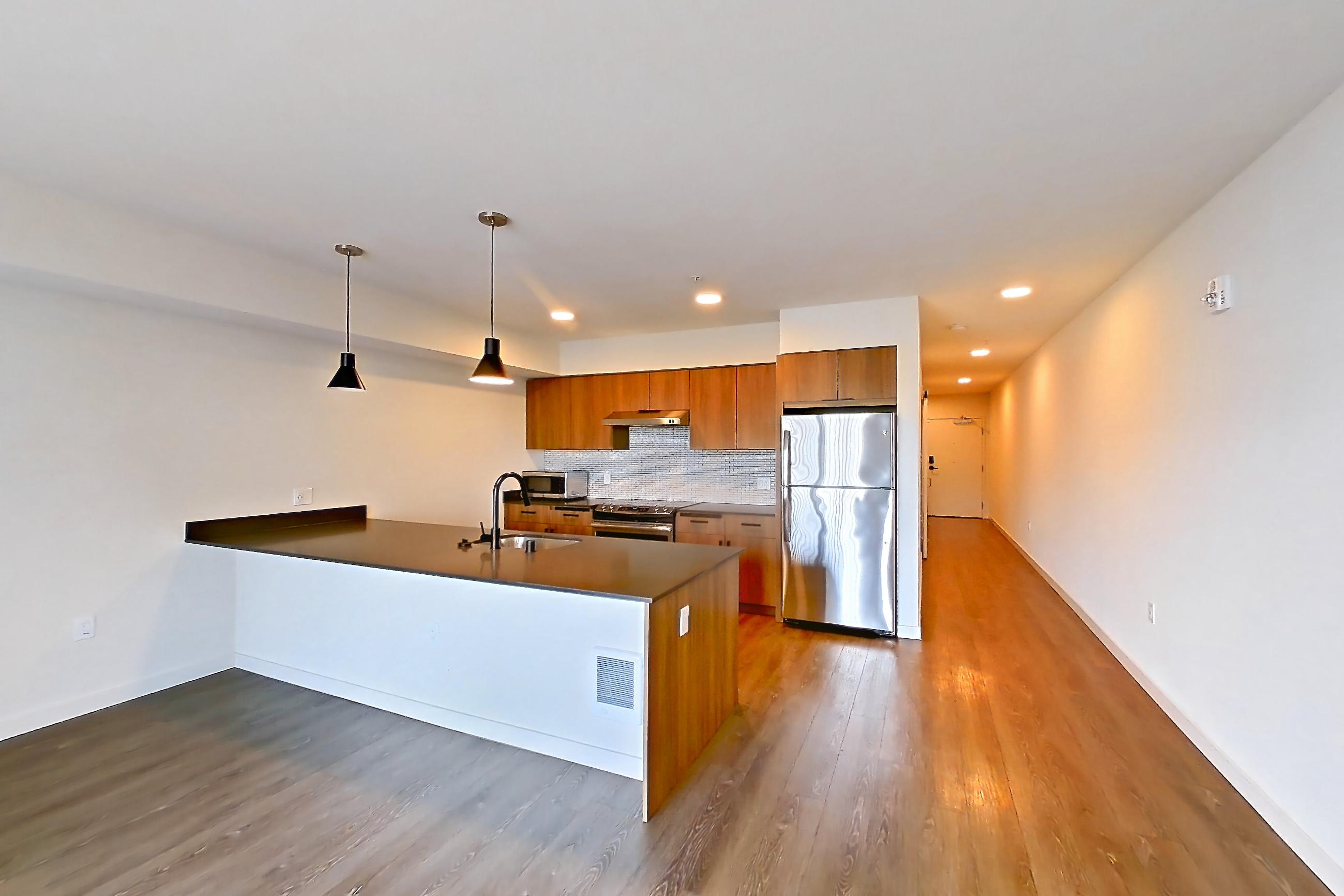 Living room with dark countertops, dark wood-finish flooring, light countertops, microwave, oven/range, refrigerator, and stainless steel appliances, Apartment 440 at Talisman