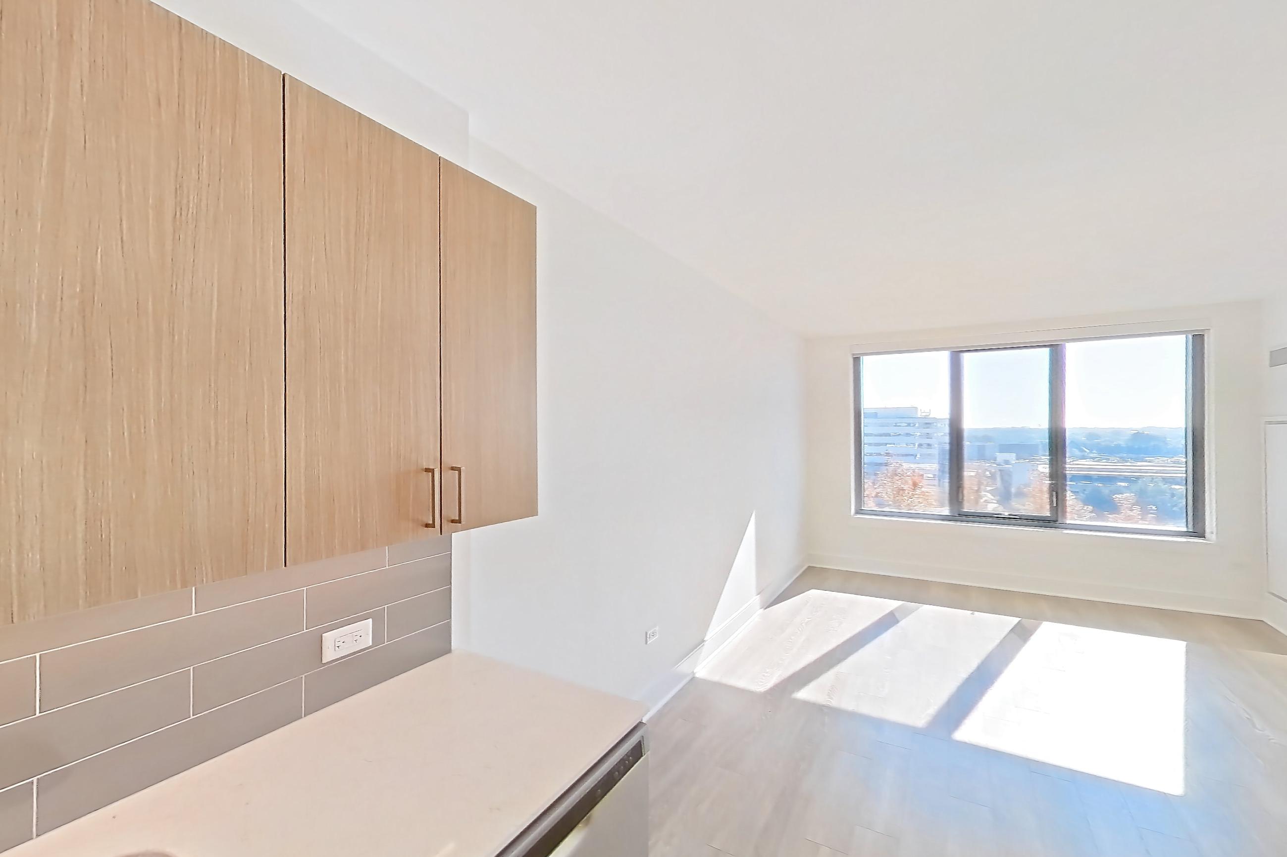 Kitchen with black appliances, dishwasher, gas range, light countertops, light stone countertops, light wood-finish flooring, microwave, oven/range, refrigerator, and stainless steel appliances, Apartment 816 at One Oak Brook Commons