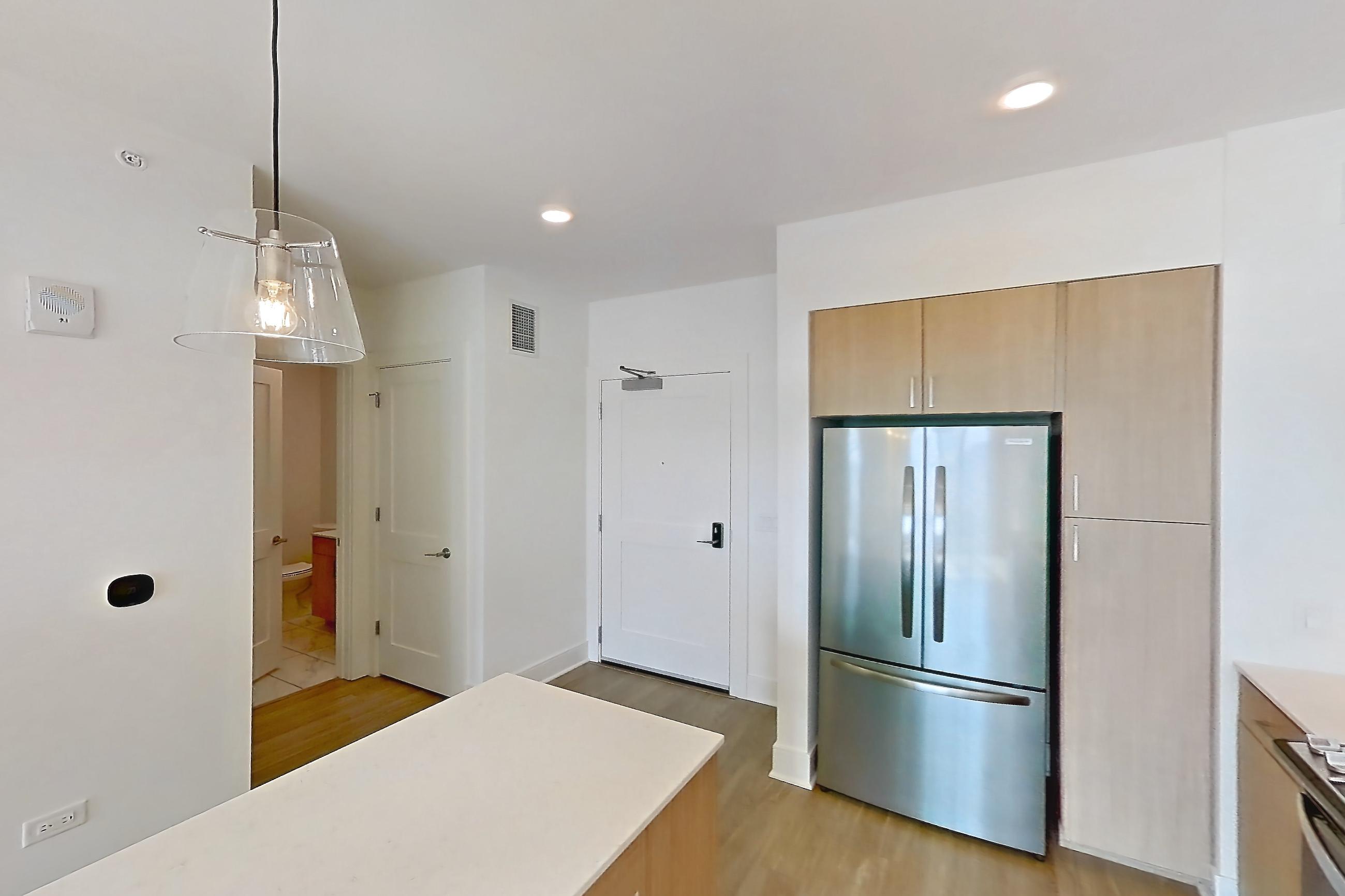 Kitchen with black appliances, dishwasher, gas range, light countertops, light stone countertops, light wood-finish flooring, microwave, oven/range, refrigerator, and stainless steel appliances, Apartment 816 at One Oak Brook Commons