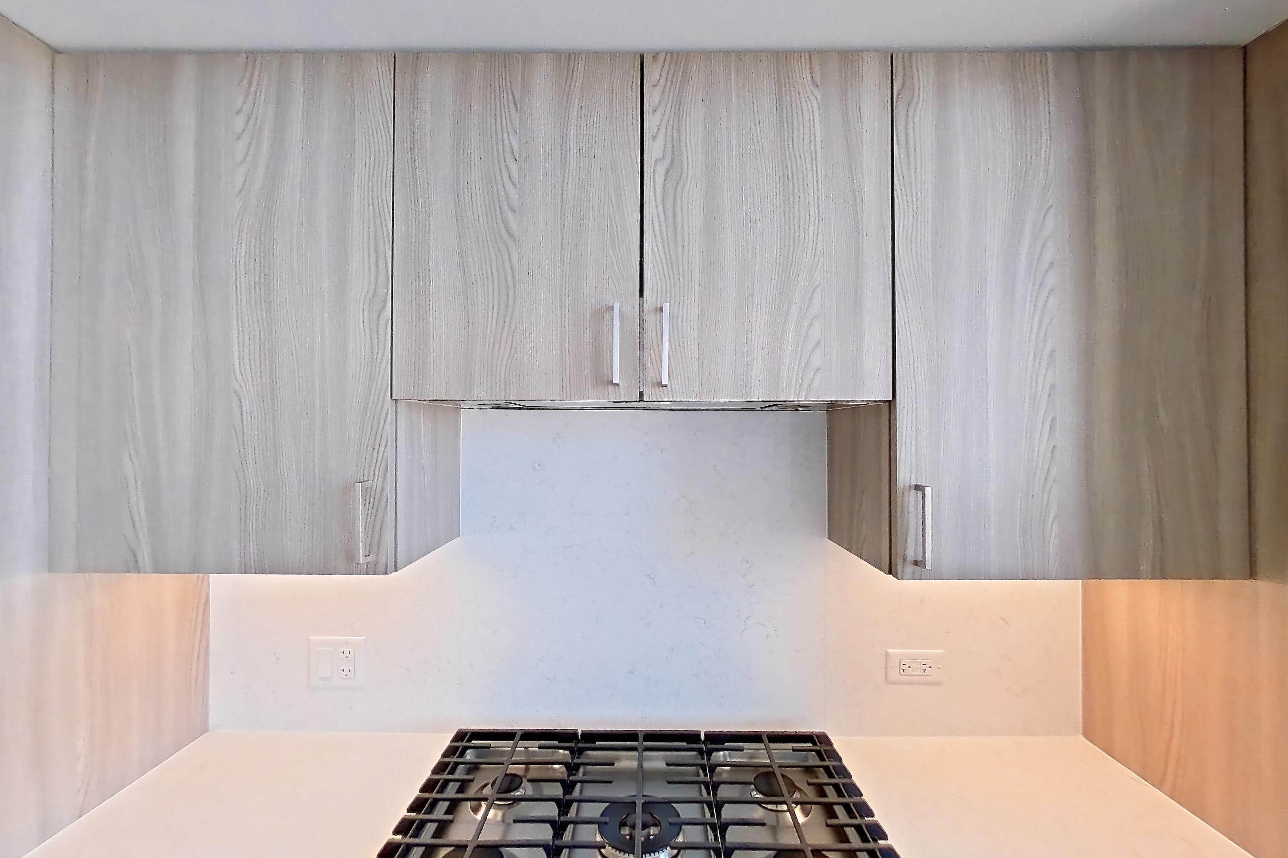 Kitchen with cooktop, dark wood-finish flooring, double oven, gas cooktop, light stone countertops, and stainless steel appliances, Apartment 1711 at One Oak Brook Commons