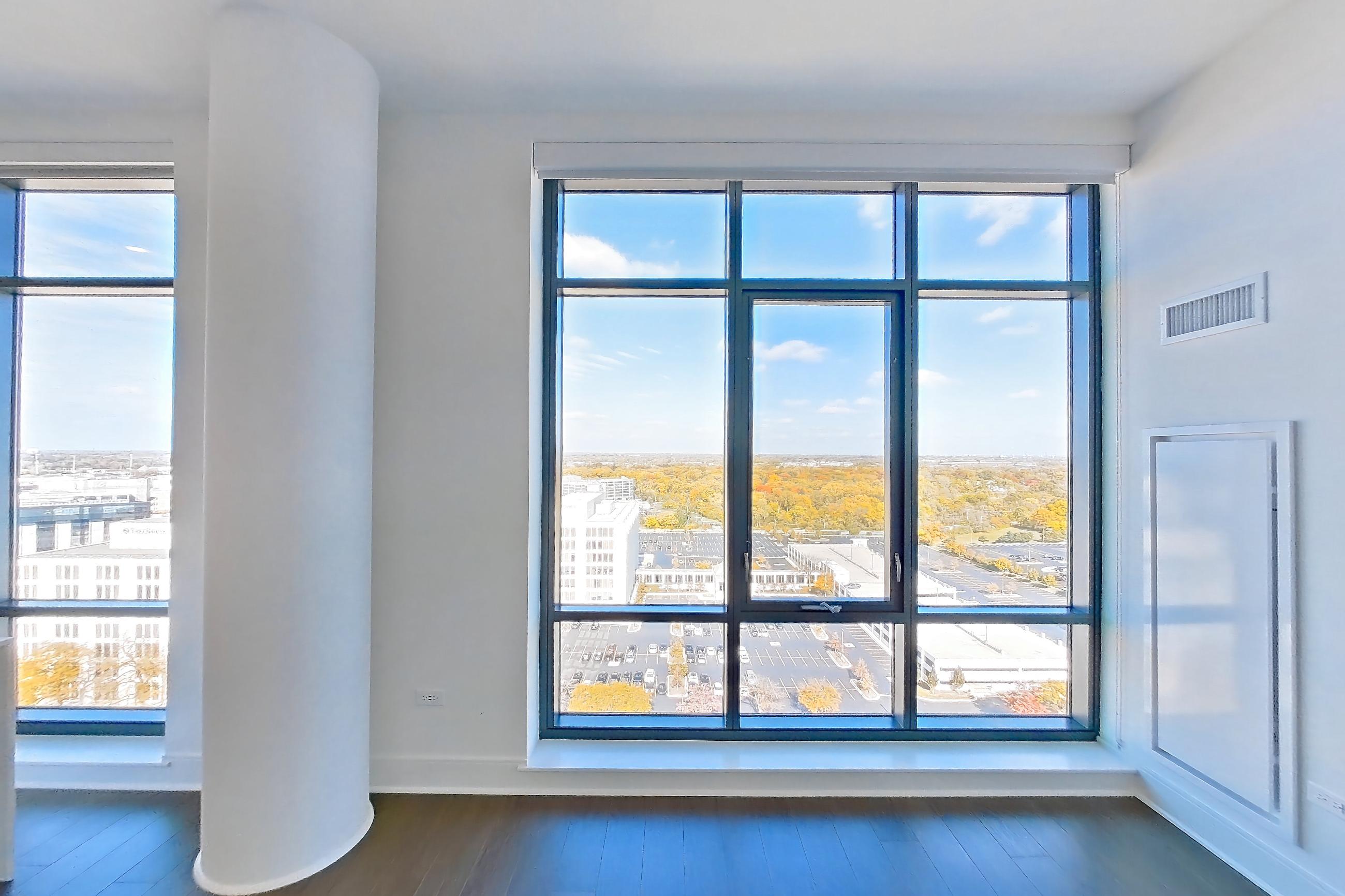 Living room with city view, cooktop, dark wood-finish flooring, double oven, gas cooktop, light stone countertops, and stainless steel appliances, Apartment 1711 at One Oak Brook Commons