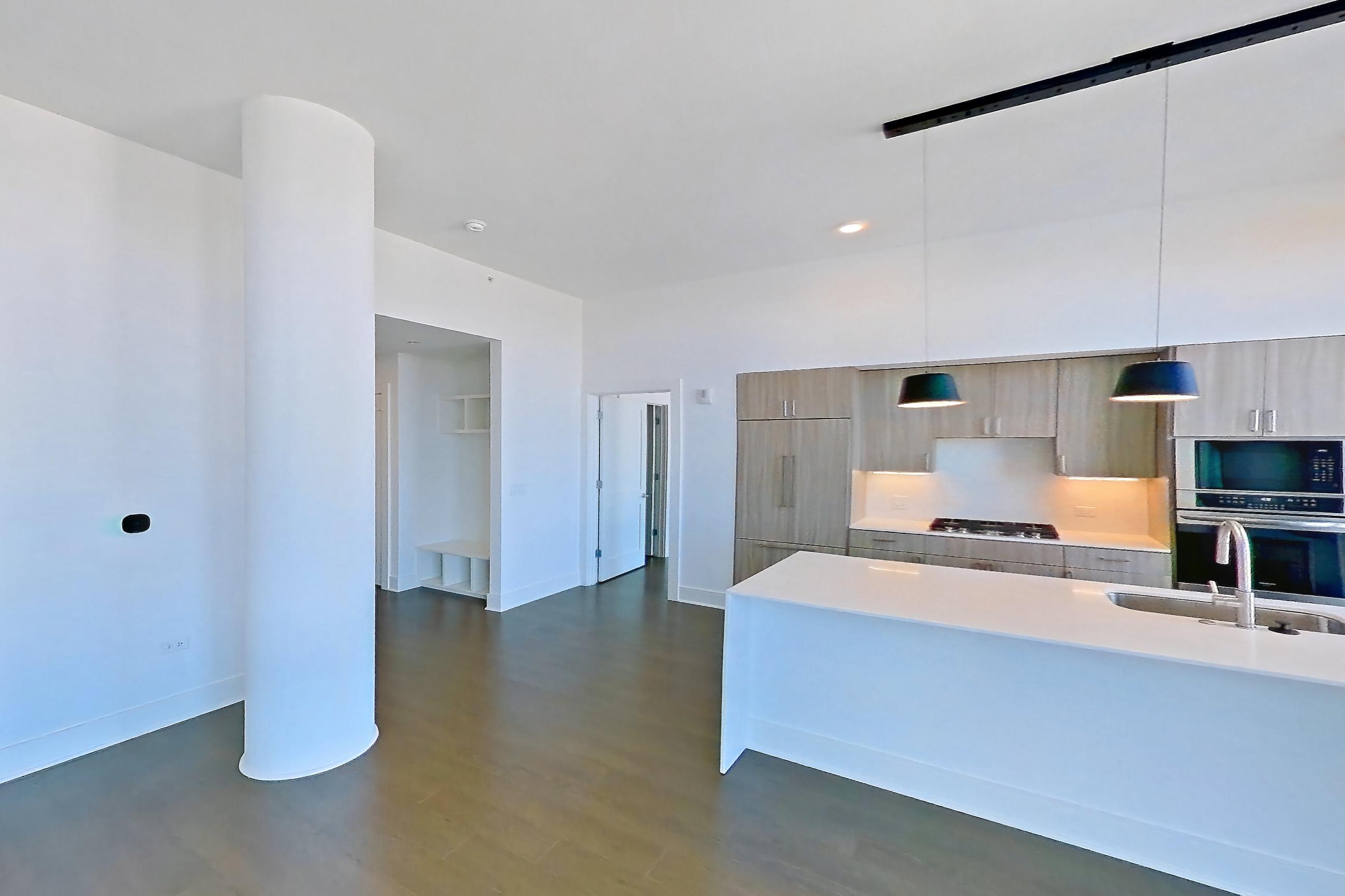 Living room with city view, cooktop, dark wood-finish flooring, double oven, gas cooktop, light stone countertops, and stainless steel appliances, Apartment 1711 at One Oak Brook Commons