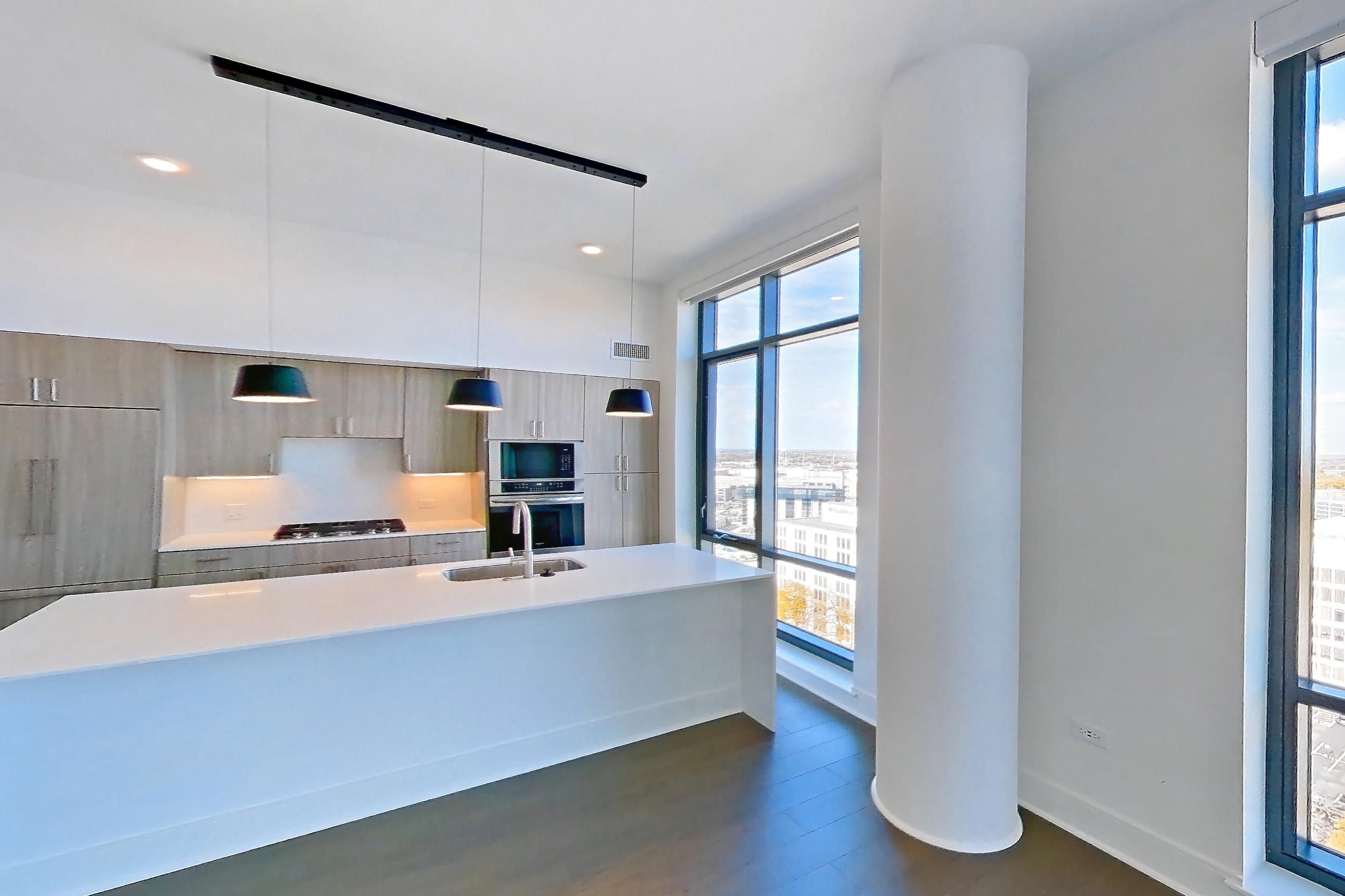 Living room with city view, cooktop, dark wood-finish flooring, double oven, gas cooktop, light stone countertops, and stainless steel appliances, Apartment 1711 at One Oak Brook Commons