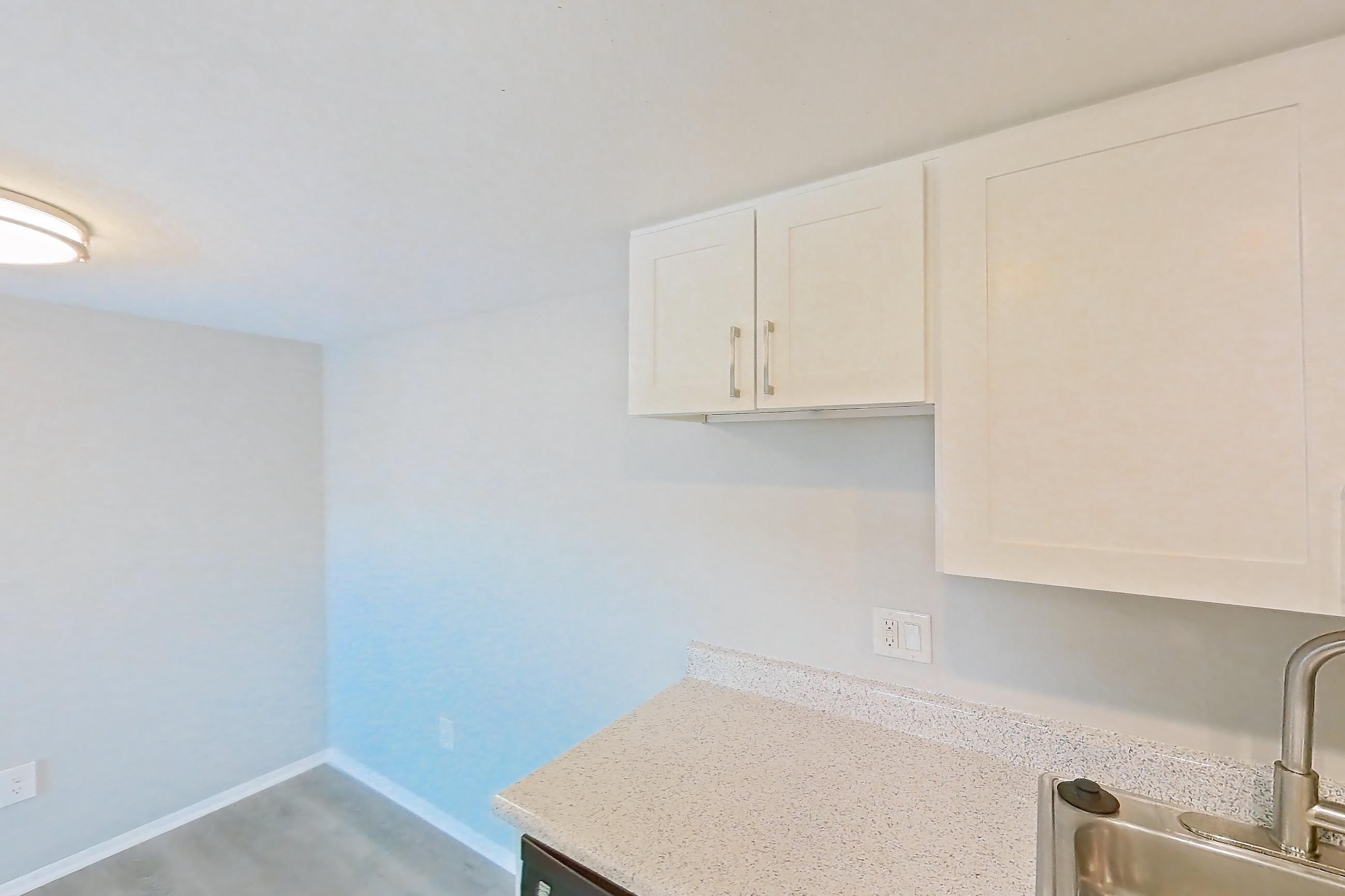 Kitchen with black appliances, dishwasher, electric range, light countertops, light stone countertops, light wood-finish flooring, microwave, oven/range, and stainless steel appliances, Apartment 01 at Avana Rancho Cucamonga