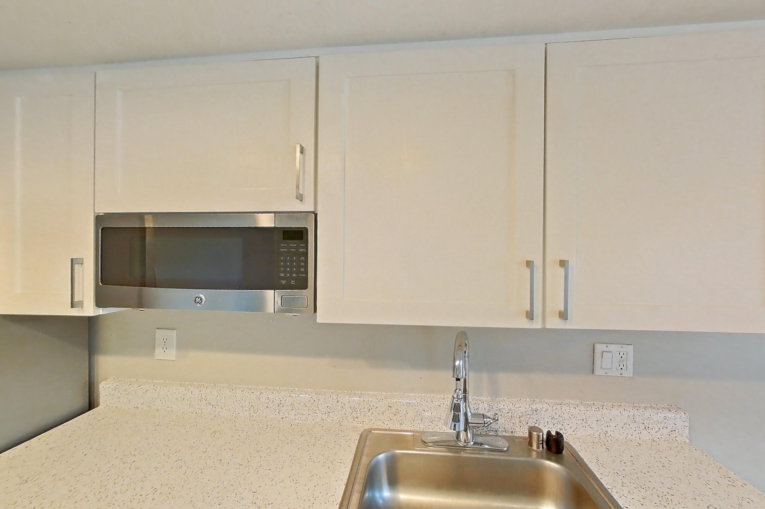 Kitchen with dishwasher, light stone countertops, light wood-finish flooring, microwave, oven/range, refrigerator, and stainless steel appliances, Apartment 07 at Avana Rancho Cucamonga