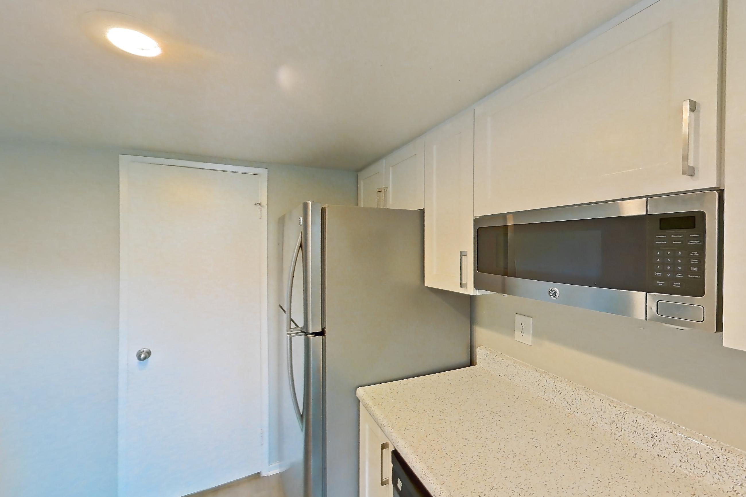 Kitchen with dishwasher, light stone countertops, light wood-finish flooring, microwave, oven/range, refrigerator, and stainless steel appliances, Apartment 07 at Avana Rancho Cucamonga