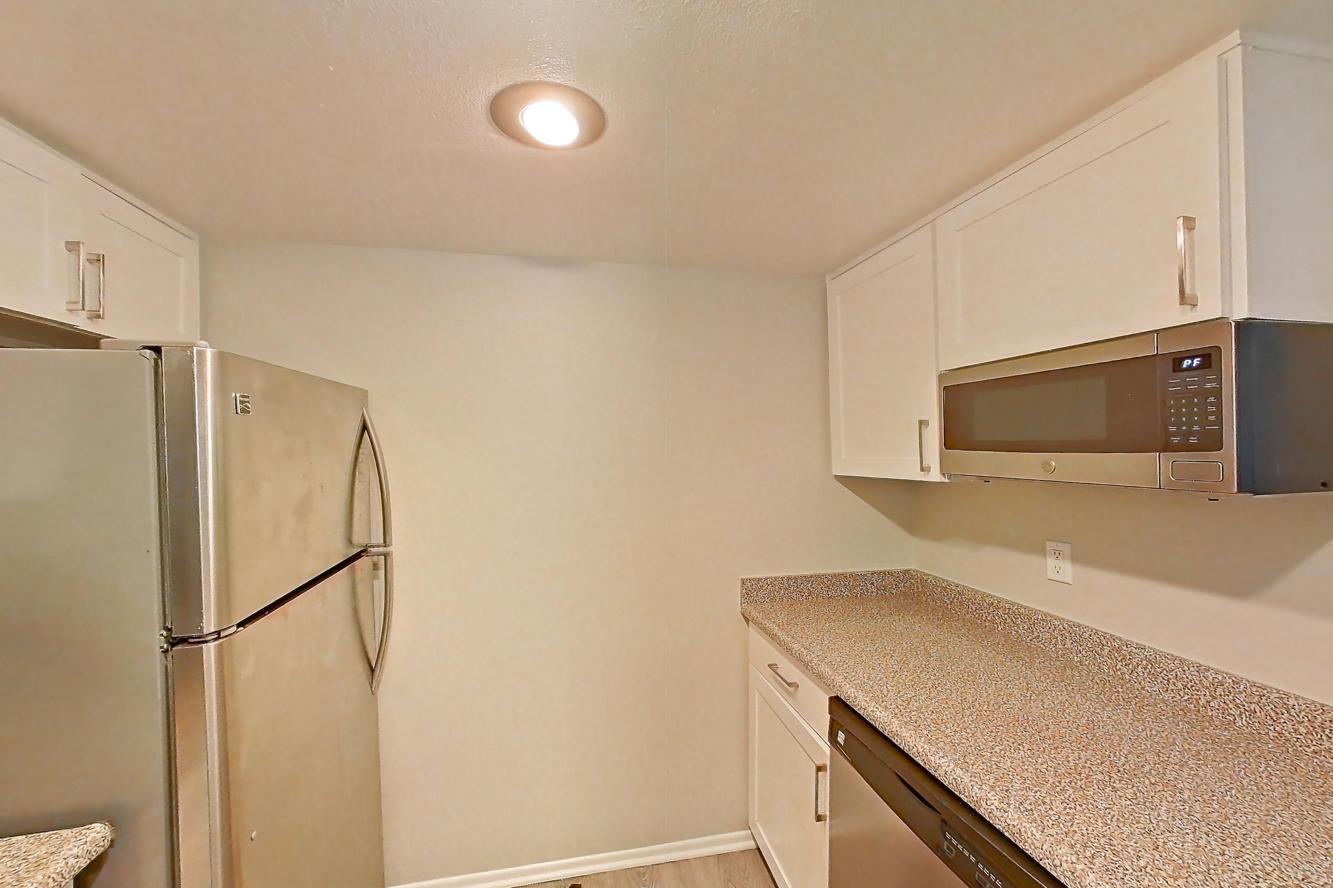 Kitchen with dishwasher, electric range, light countertops, light stone countertops, light wood-finish flooring, oven/range, range hood, and stainless steel appliances, Apartment 01 at Avana Rancho Cucamonga