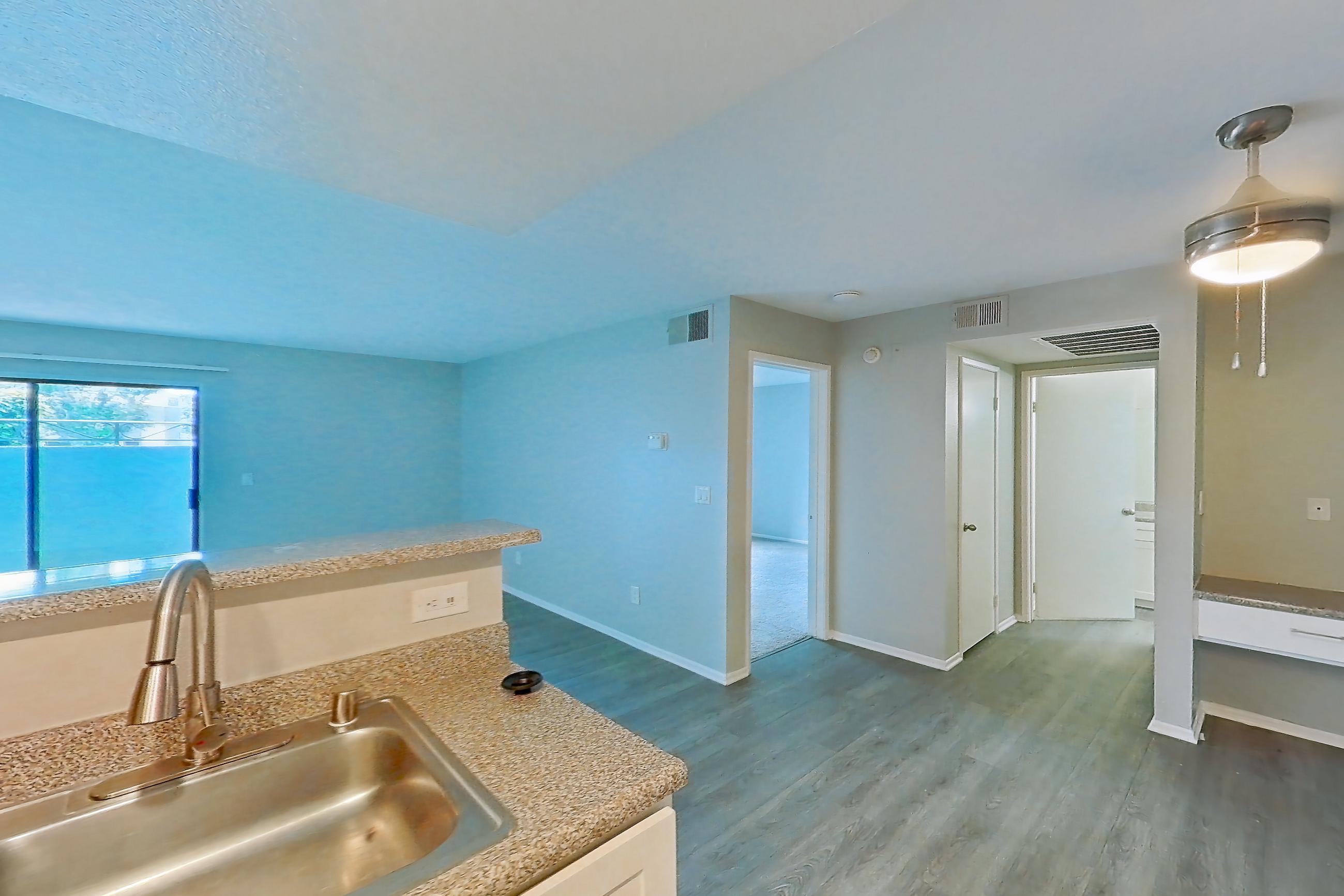 Kitchen with dishwasher, electric range, light countertops, light stone countertops, light wood-finish flooring, oven/range, range hood, and stainless steel appliances, Apartment 01 at Avana Rancho Cucamonga