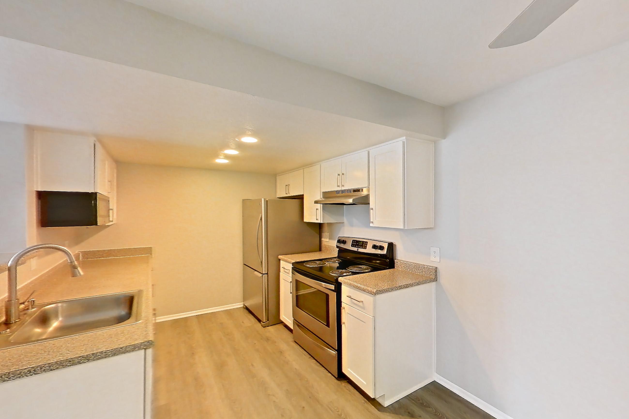 Dining room with dark stone countertops, dark wood-finish flooring, electric range, light countertops, light wood-finish flooring, oven/range, range hood, refrigerator, and stainless steel appliances, Apartment 23 at Avana Rancho Cucamonga