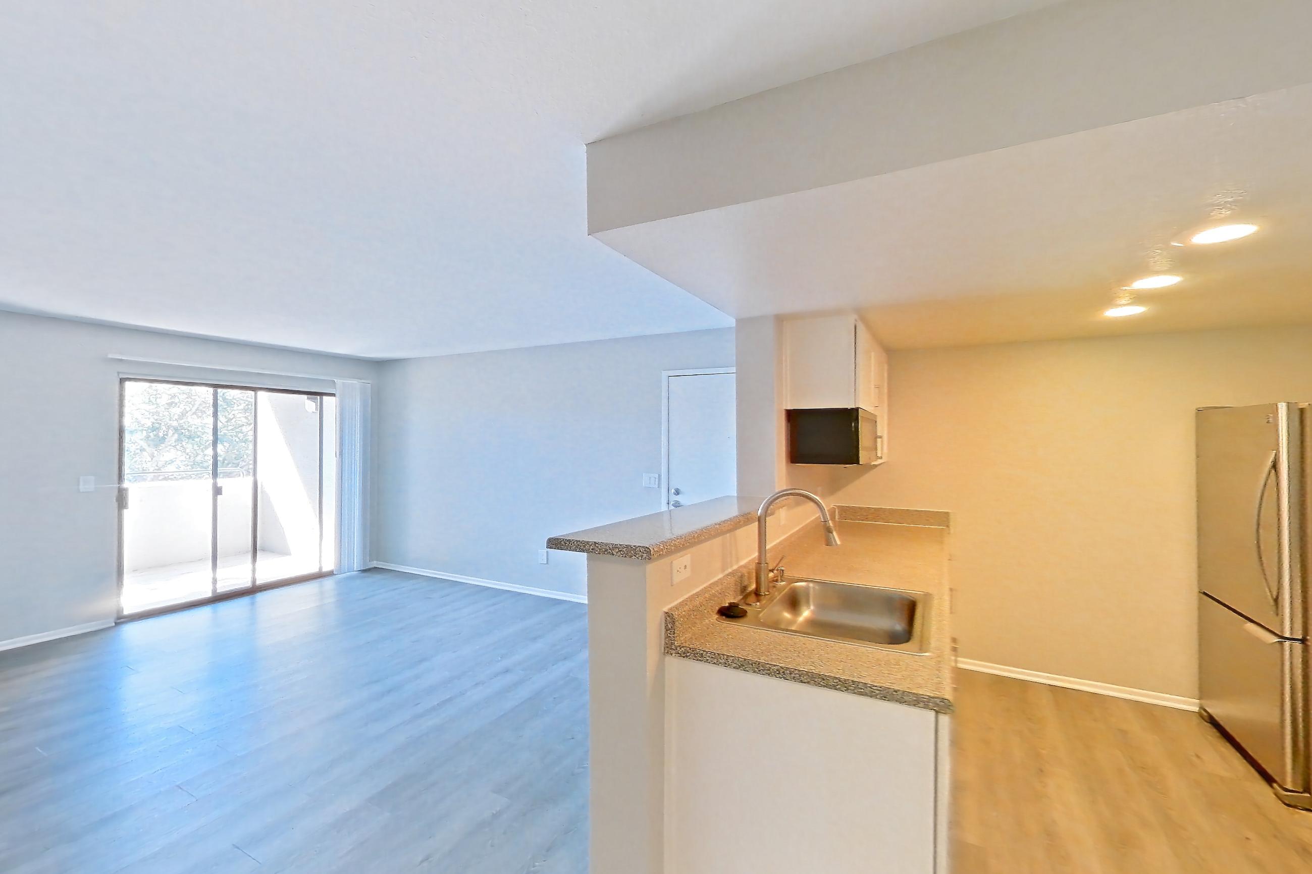 Dining room with dark stone countertops, dark wood-finish flooring, electric range, light countertops, light wood-finish flooring, oven/range, range hood, refrigerator, and stainless steel appliances, Apartment 23 at Avana Rancho Cucamonga