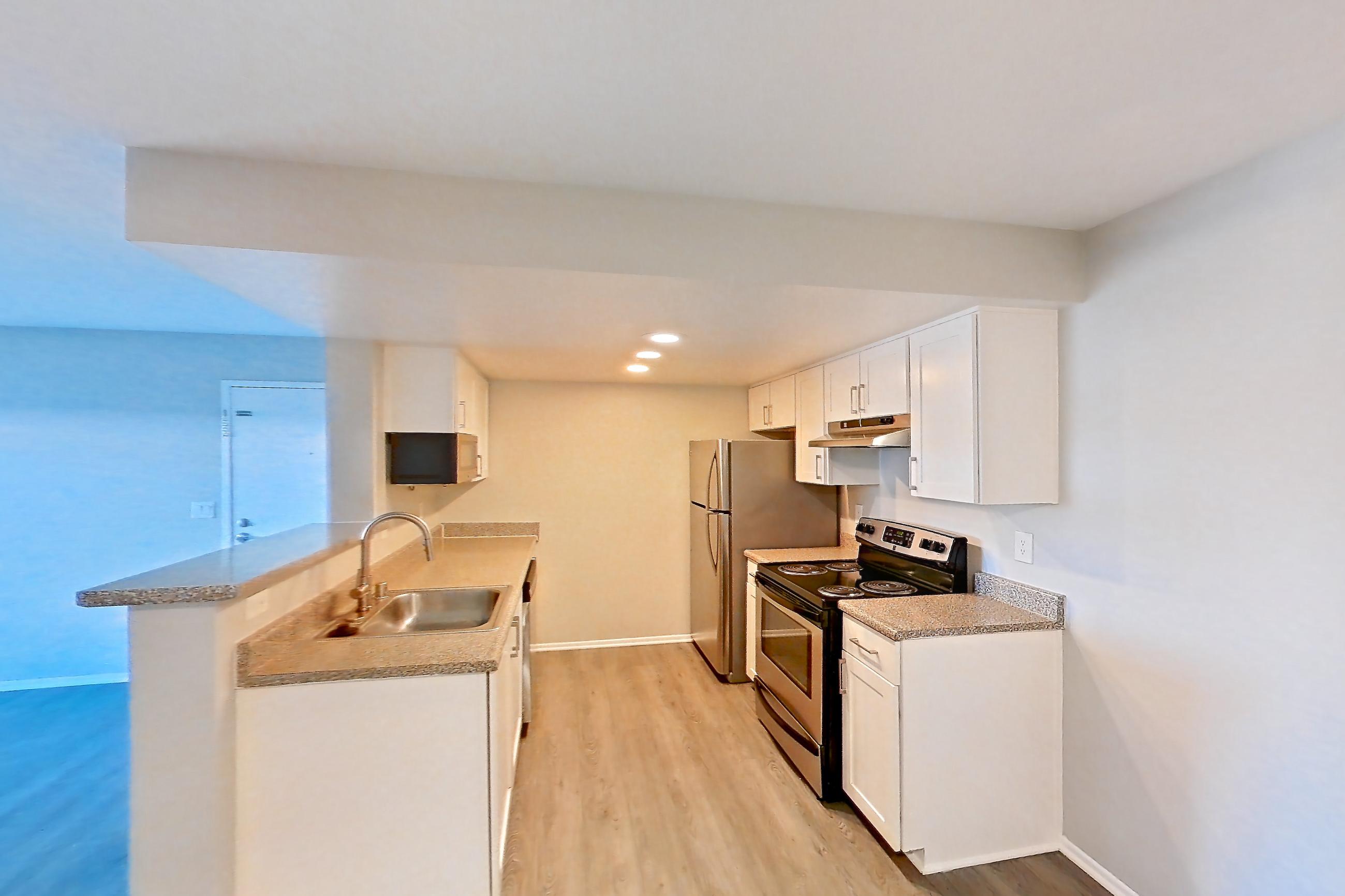 Dining room with electric range, light countertops, light wood-finish flooring, oven/range, refrigerator, and stainless steel appliances, Apartment 19 at Avana Rancho Cucamonga