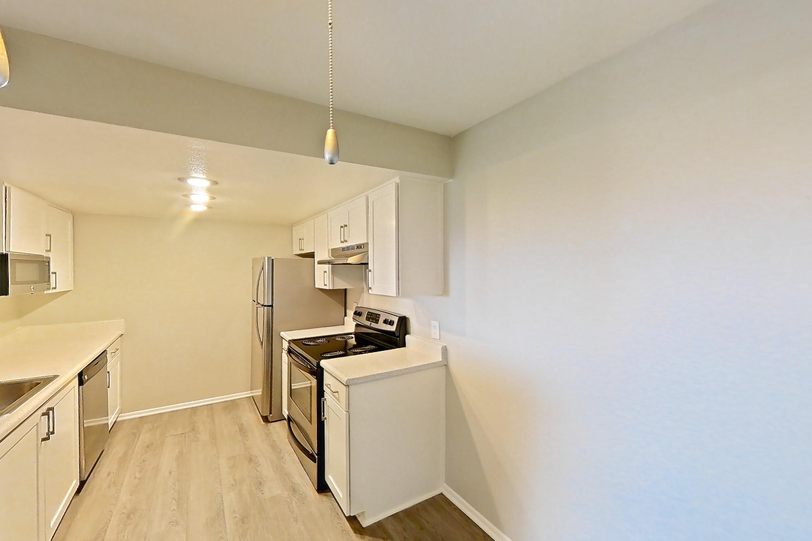 Dining room with dark wood-finish flooring, electric range, light countertops, light wood-finish flooring, oven/range, and stainless steel appliances, Apartment 23 at Avana Rancho Cucamonga