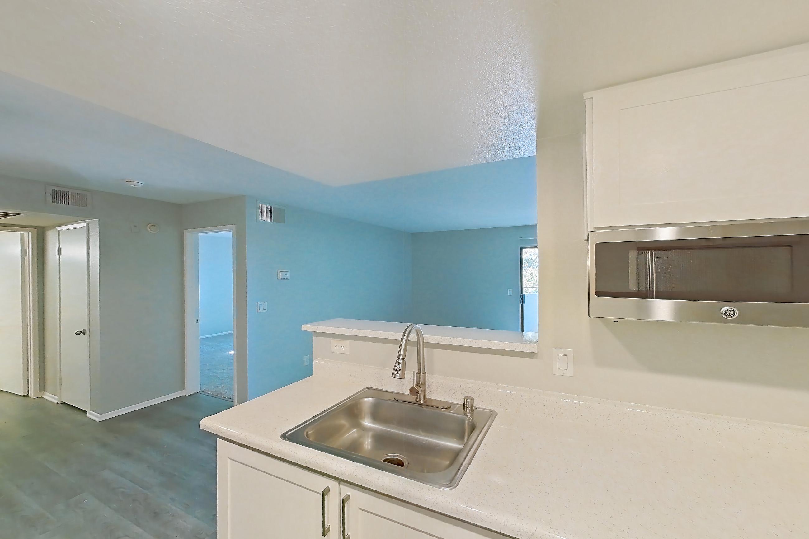 Kitchen with dishwasher, electric range, light countertops, light wood-finish flooring, oven/range, range hood, refrigerator, and stainless steel appliances, Apartment 23 at Avana Rancho Cucamonga