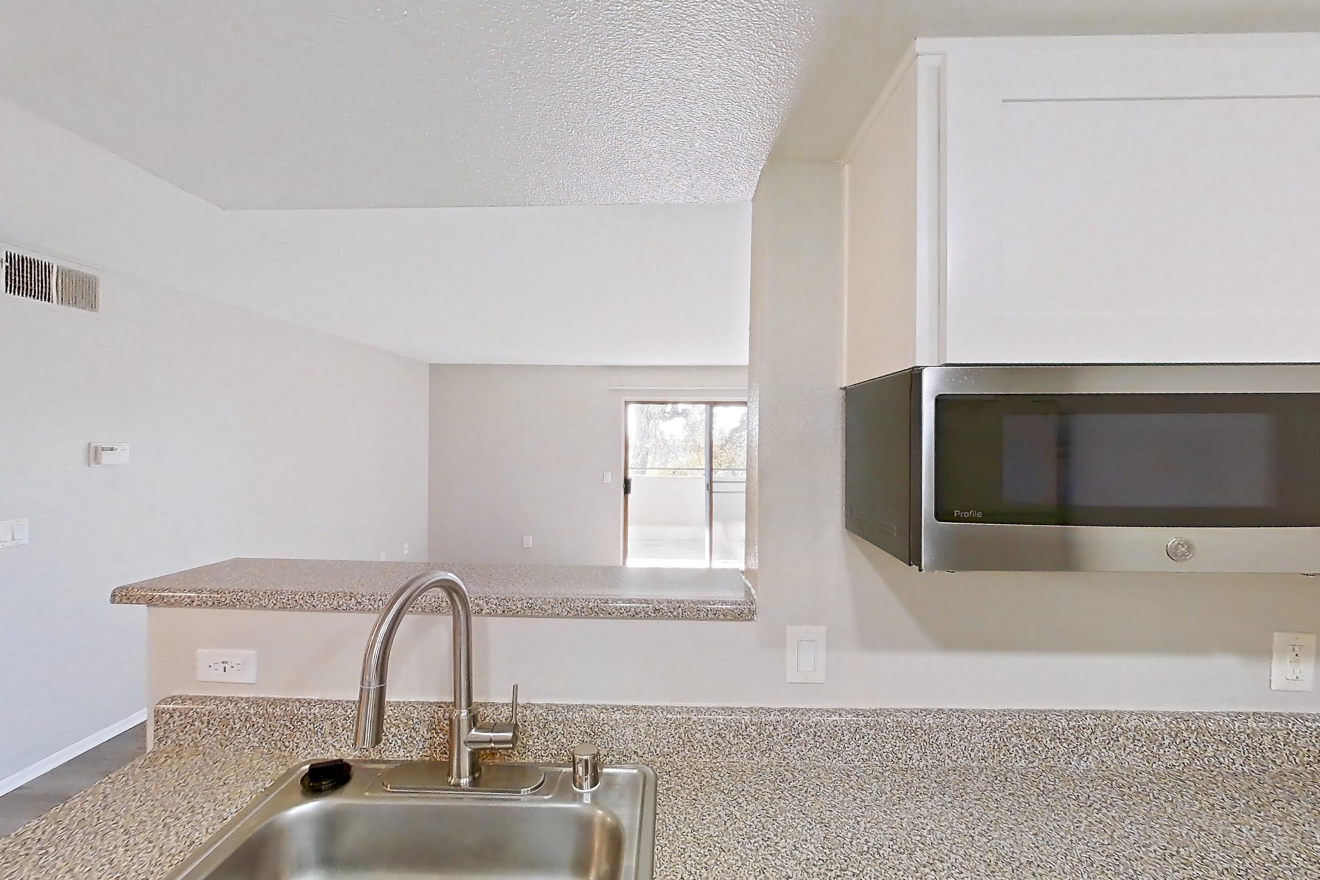 Kitchen with dishwasher, electric range, light stone countertops, light wood-finish flooring, microwave, oven/range, refrigerator, and stainless steel appliances, Apartment 22 at Avana Rancho Cucamonga