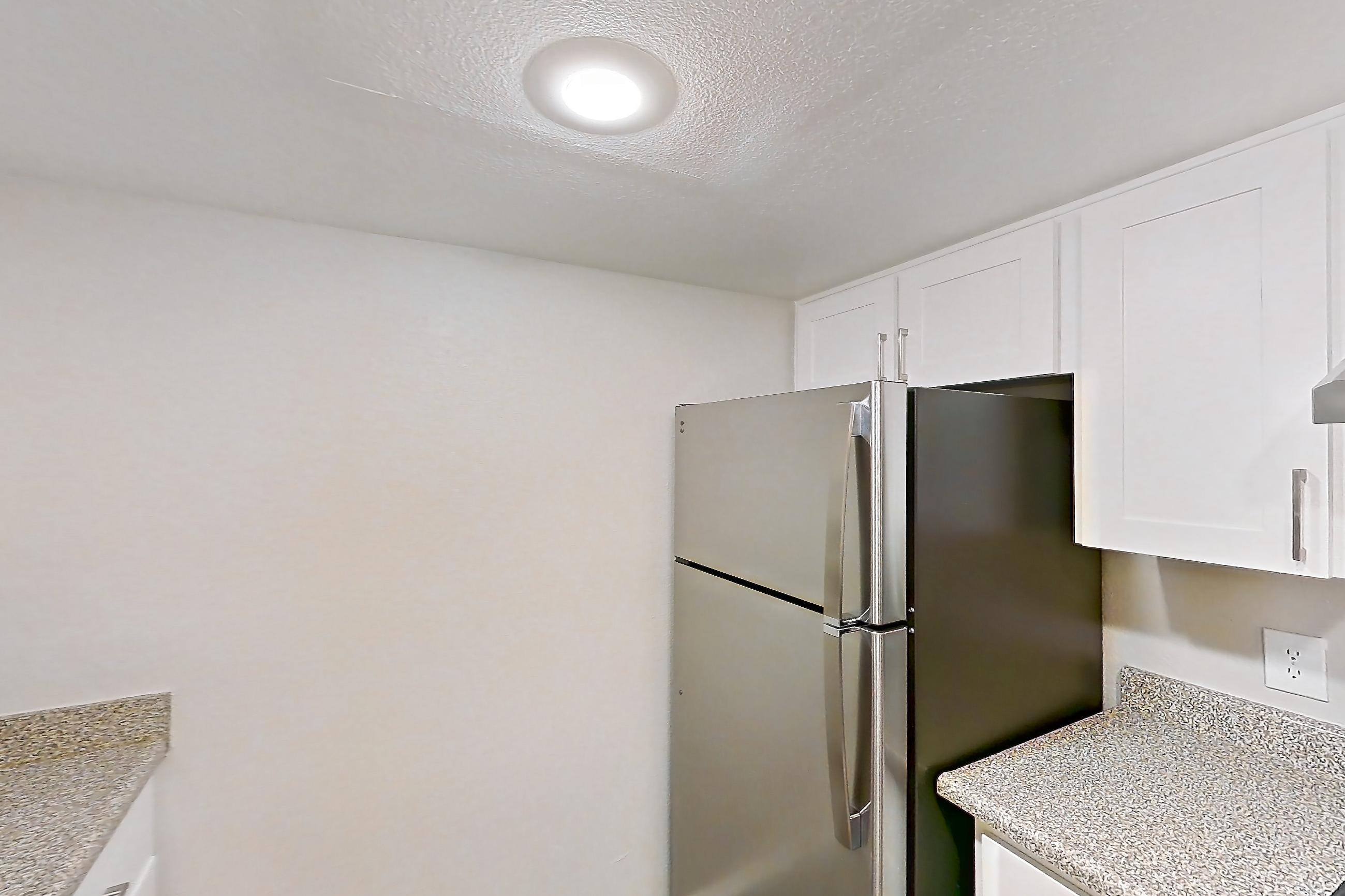 Kitchen with dishwasher, electric range, light stone countertops, light wood-finish flooring, microwave, oven/range, refrigerator, and stainless steel appliances, Apartment 22 at Avana Rancho Cucamonga