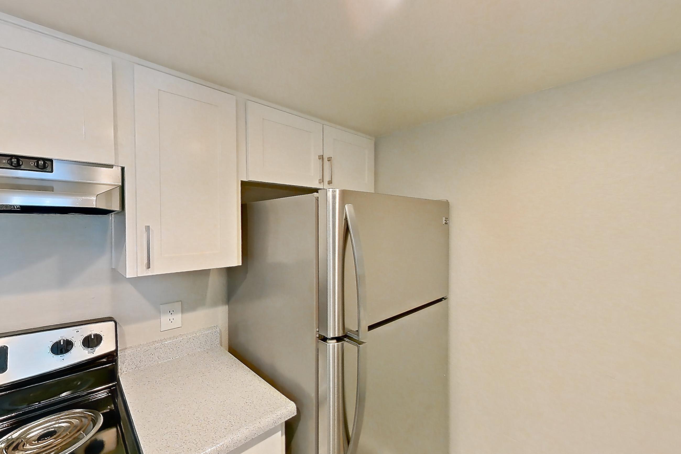 Kitchen with dishwasher, light countertops, light stone countertops, light wood-finish flooring, oven/range, refrigerator, stainless steel appliances, and white appliances, Apartment 05 at Avana Rancho Cucamonga