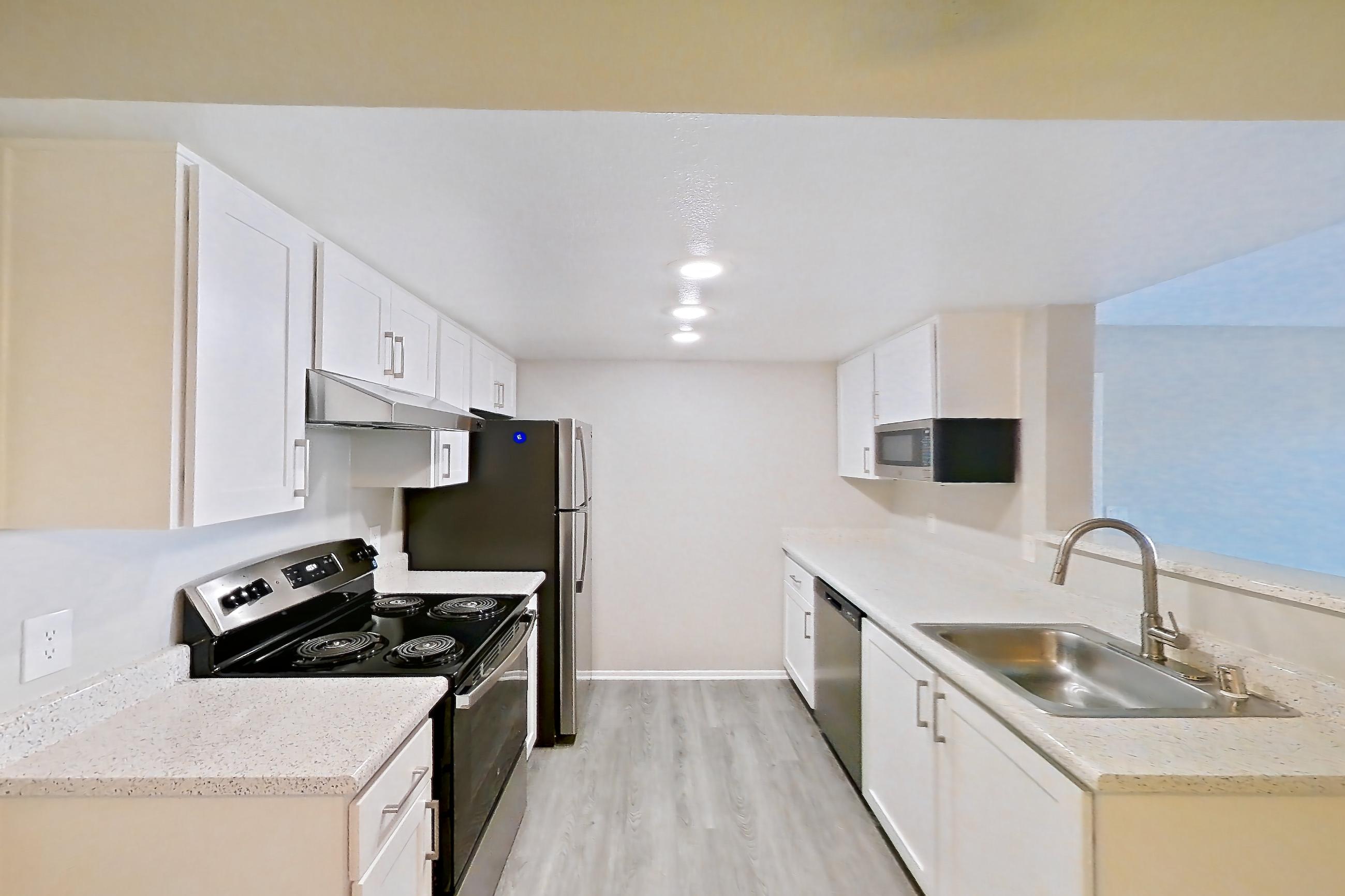 Dining room with black appliances, dishwasher, electric range, light countertops, light stone countertops, light wood-finish flooring, oven/range, and stainless steel appliances, Apartment 12 at Avana Rancho Cucamonga