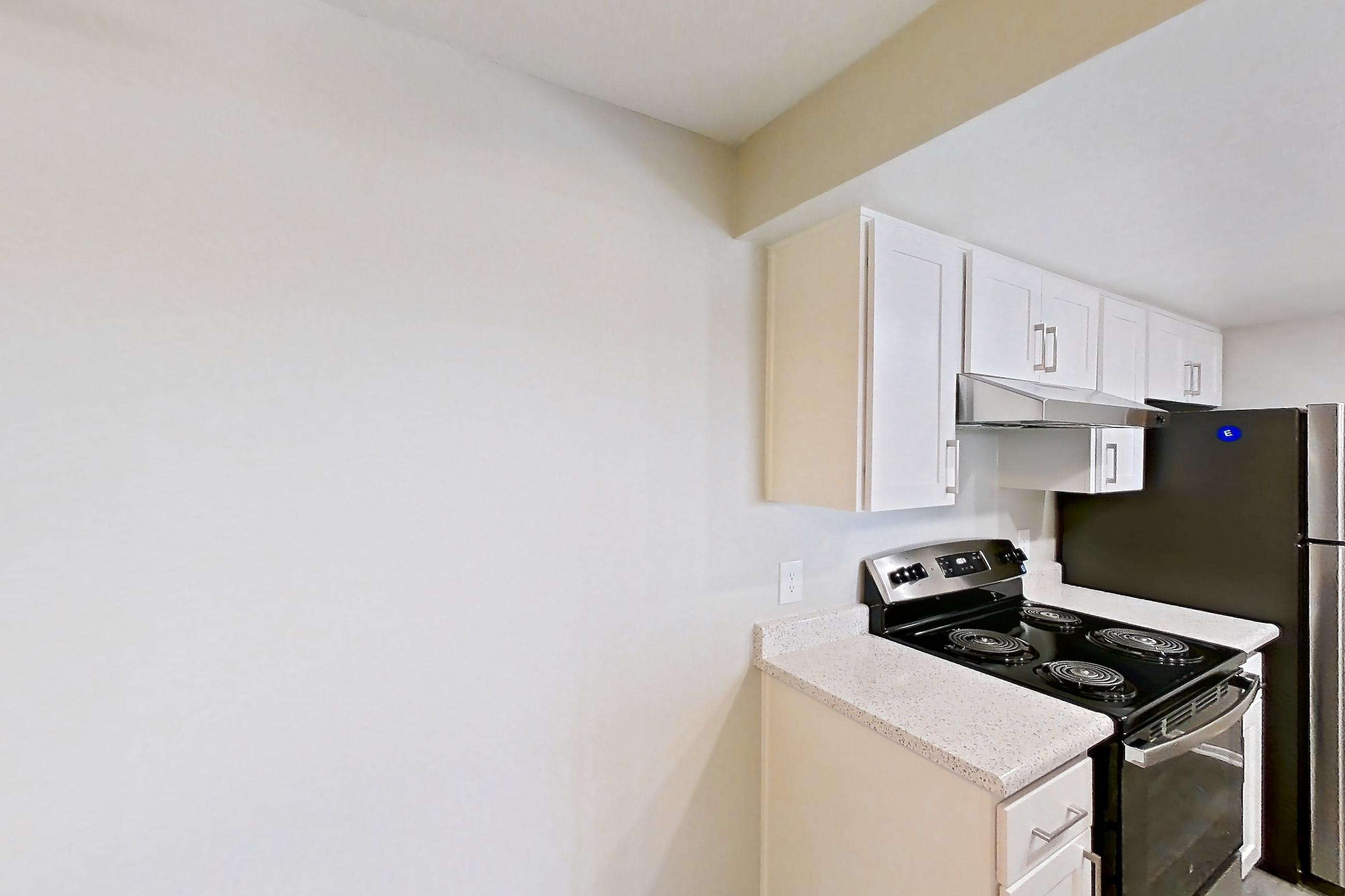 Dining room with black appliances, dishwasher, electric range, light countertops, light stone countertops, light wood-finish flooring, oven/range, and stainless steel appliances, Apartment 12 at Avana Rancho Cucamonga