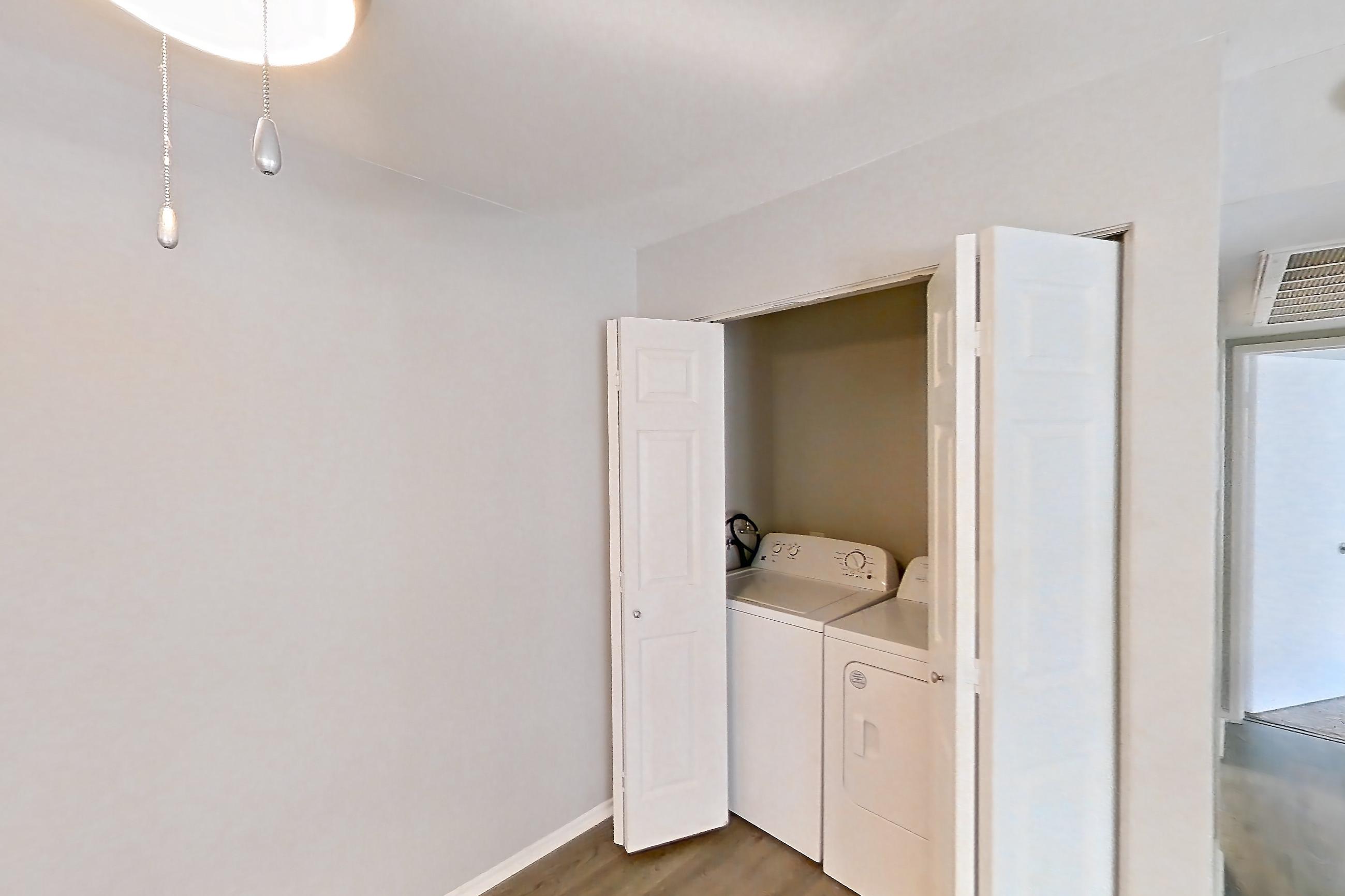 Dining room with dark carpet, dark wood-finish flooring, electric range, in-unit laundry, light countertops, light wood-finish flooring, oven/range, refrigerator, and stainless steel appliances, Apartment 14 at Avana Rancho Cucamonga