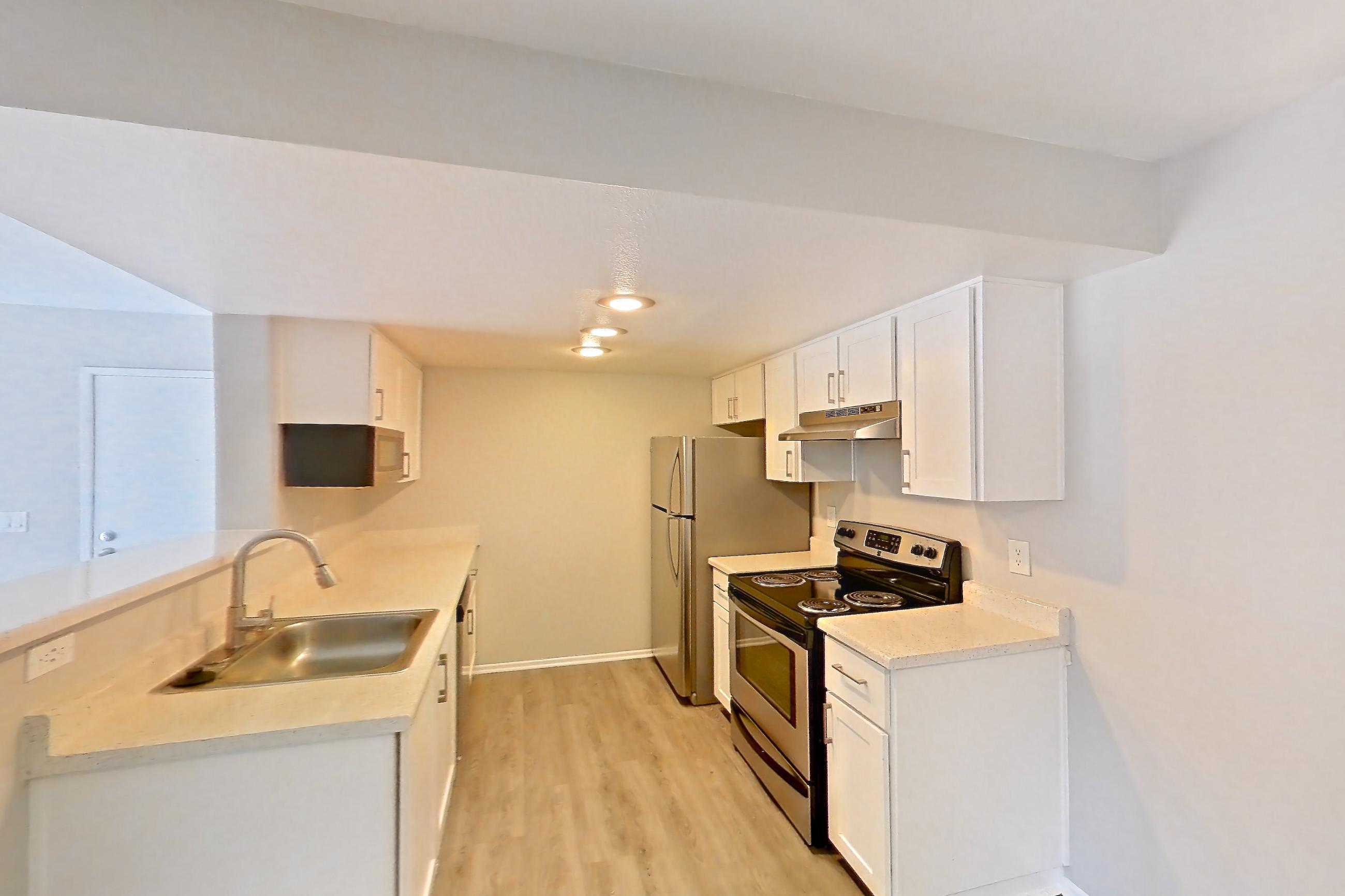 Dining room with dark carpet, dark wood-finish flooring, electric range, in-unit laundry, light countertops, light wood-finish flooring, oven/range, refrigerator, and stainless steel appliances, Apartment 14 at Avana Rancho Cucamonga