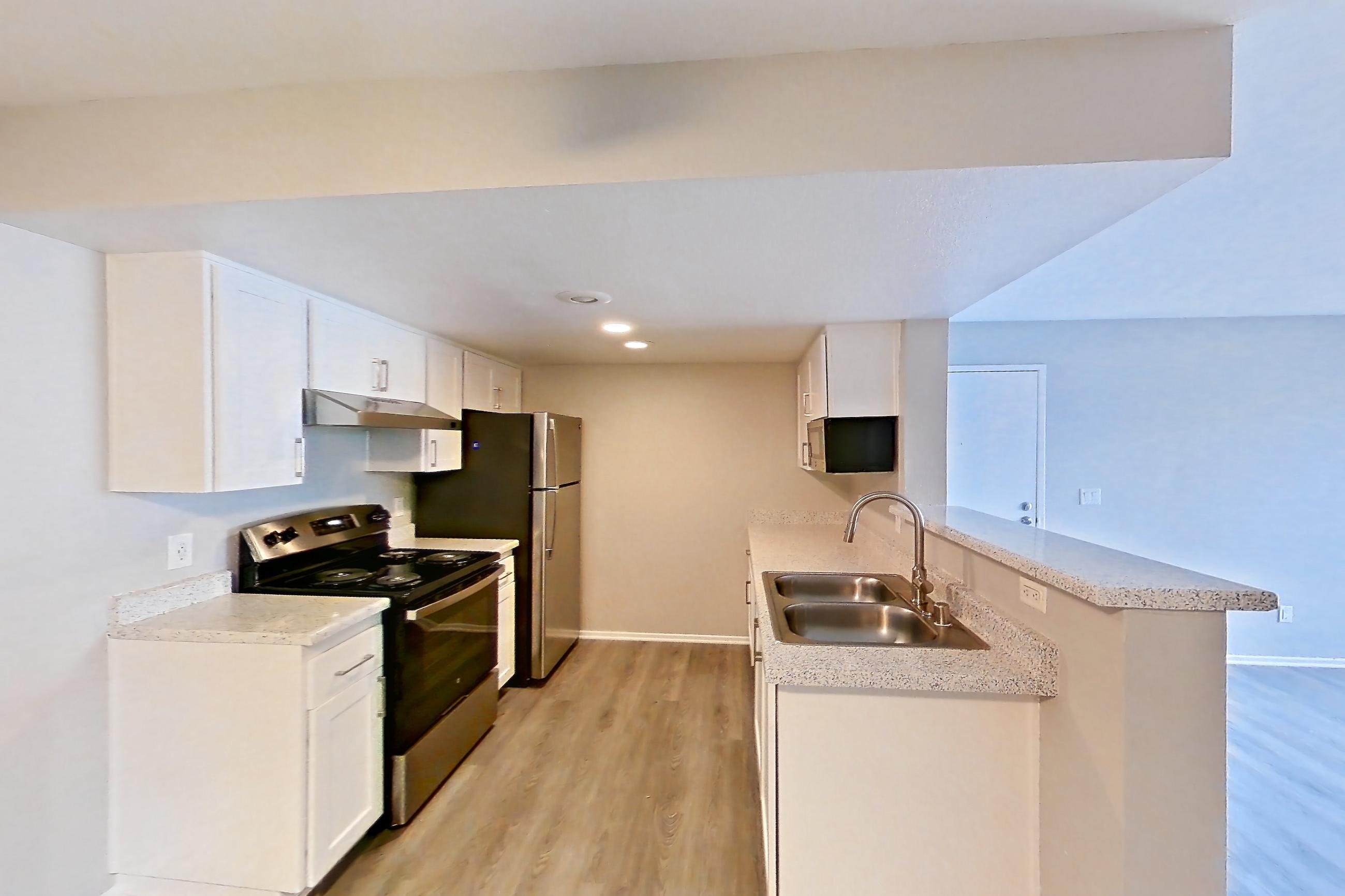 Dining room with dark wood-finish flooring, electric range, light stone countertops, light wood-finish flooring, oven/range, range hood, refrigerator, and stainless steel appliances, Apartment 21 at Avana Rancho Cucamonga
