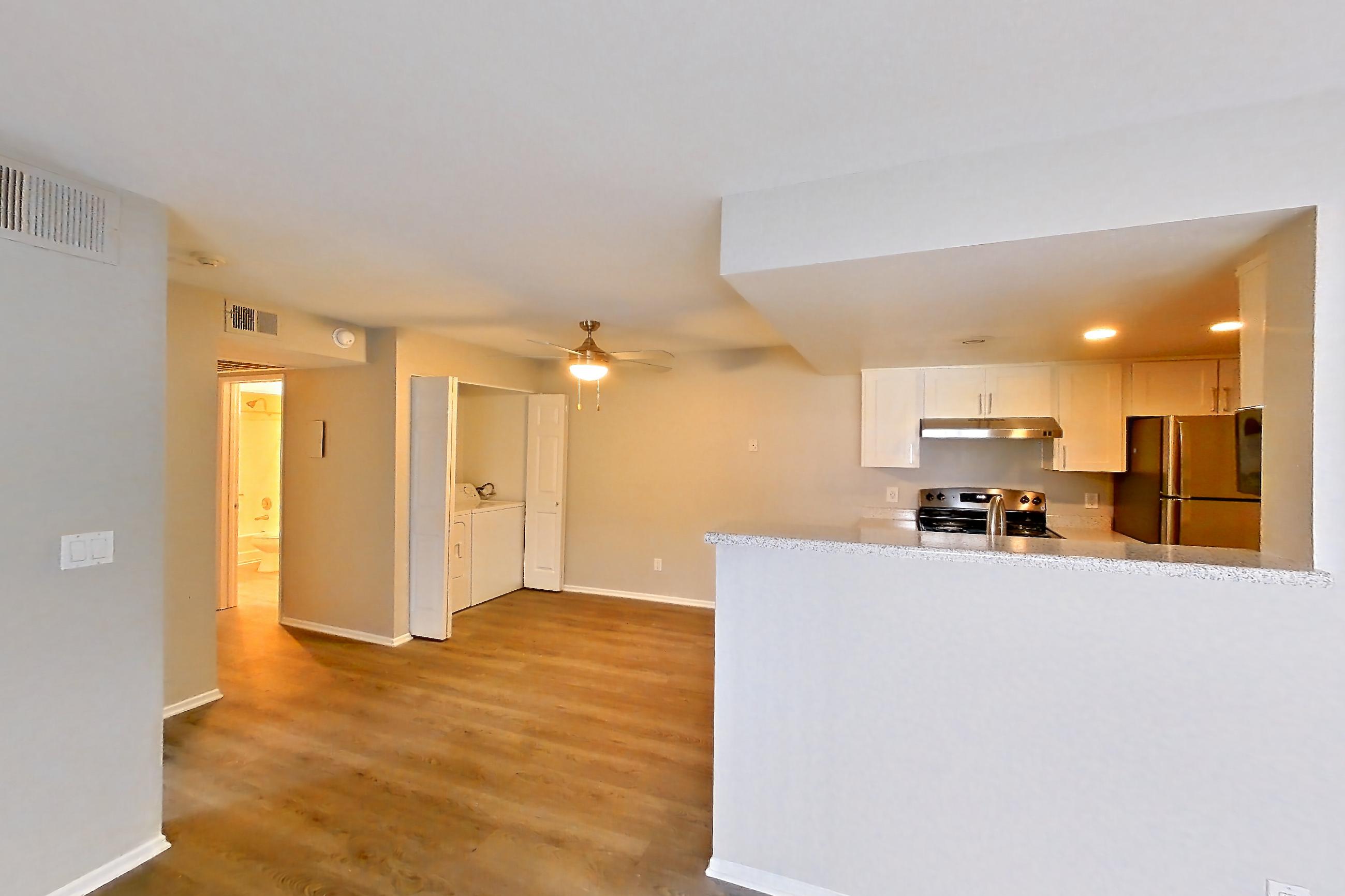 Living room with dark wood-finish flooring, electric range, light stone countertops, oven/range, refrigerator, and stainless steel appliances, Apartment 21 at Avana Rancho Cucamonga