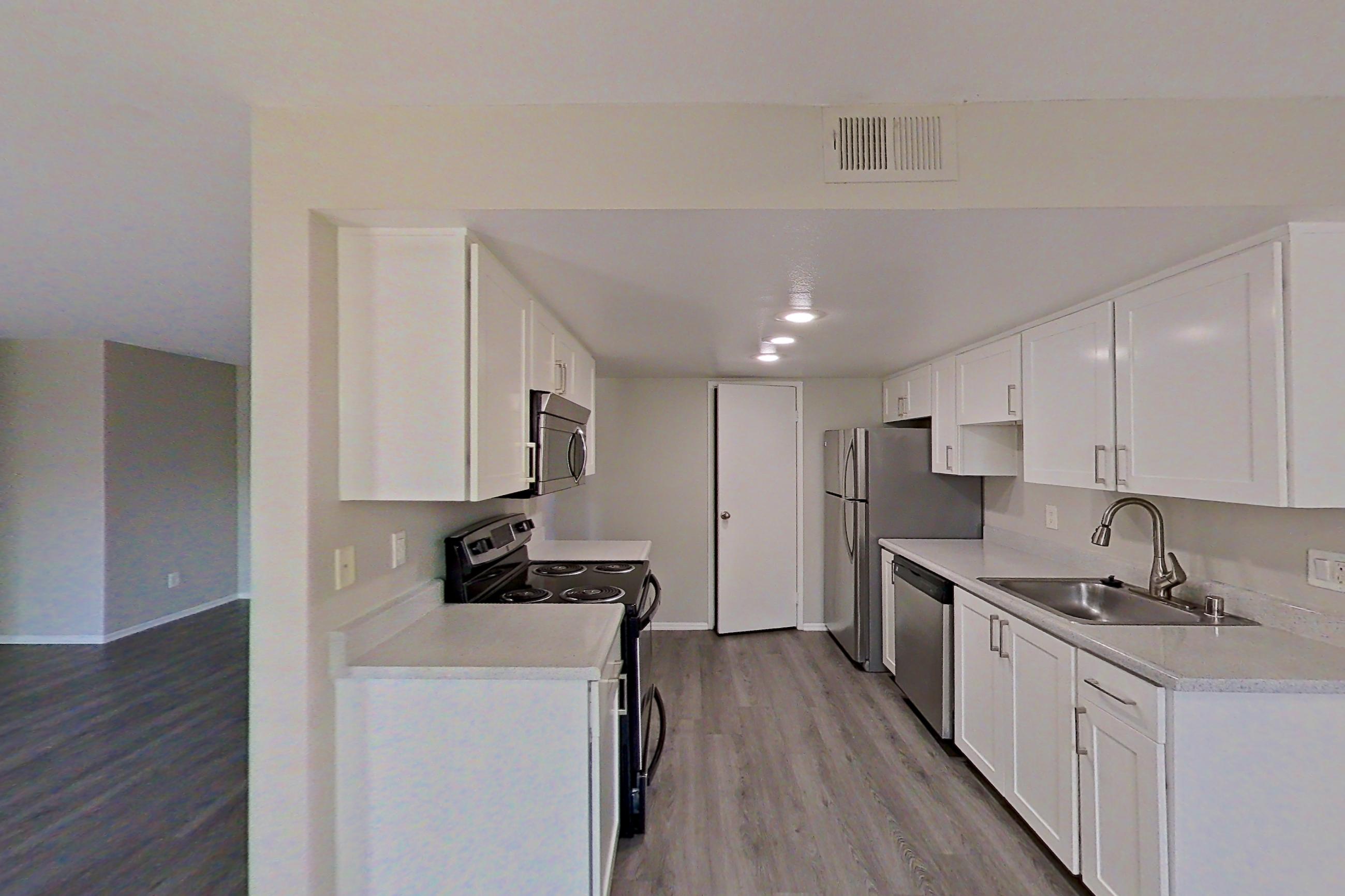 Dining area with dark wood-finish flooring, electric range, light countertops, oven/range, and stainless steel appliances, Apartment 07 at Avana Rancho Cucamonga