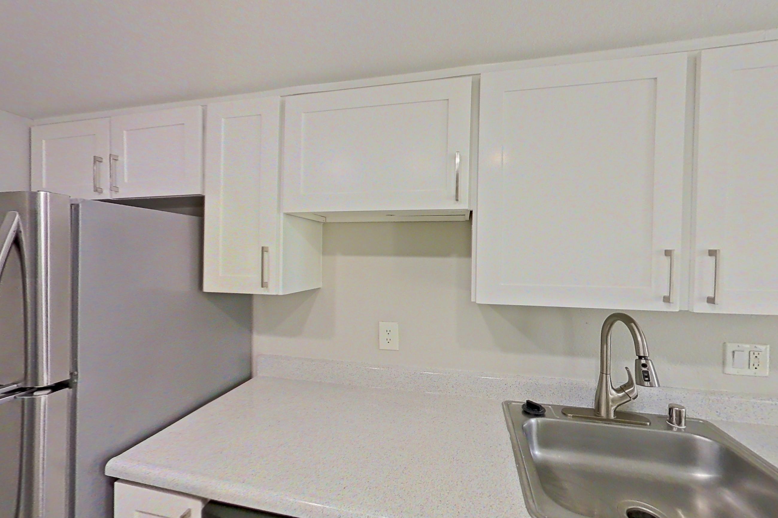 Kitchen with dishwasher, electric range, light countertops, light wood-finish flooring, microwave, oven/range, refrigerator, and stainless steel appliances, Apartment 07 at Avana Rancho Cucamonga