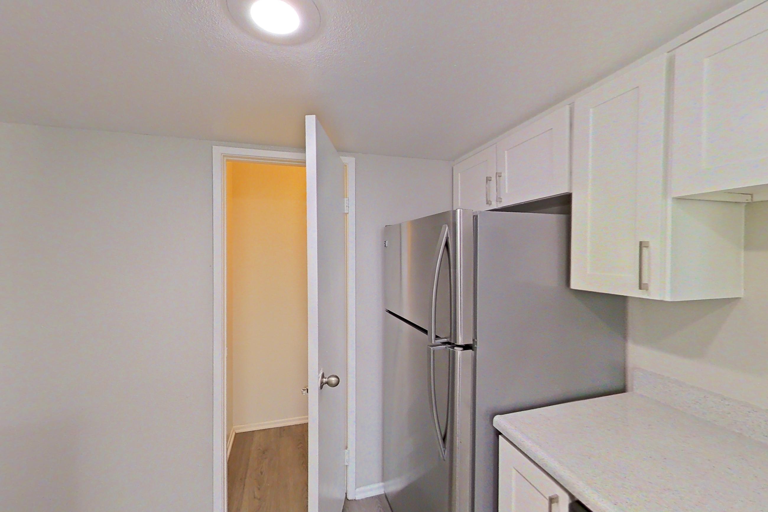Kitchen with dishwasher, electric range, light countertops, light wood-finish flooring, microwave, oven/range, refrigerator, and stainless steel appliances, Apartment 07 at Avana Rancho Cucamonga