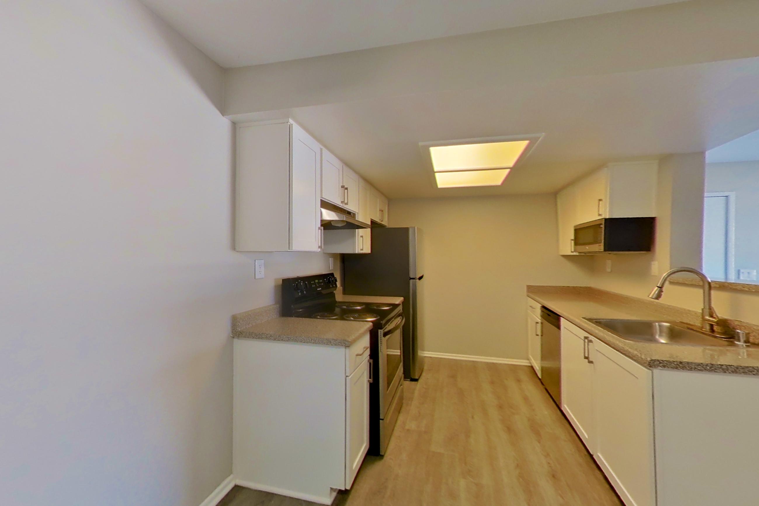 Dining area with black appliances, dishwasher, electric range, light countertops, light wood-finish flooring, oven/range, and stainless steel appliances, Apartment 08 at Avana Rancho Cucamonga